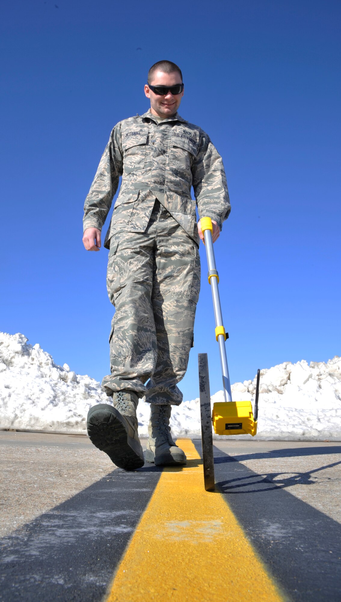U.S. Air Force Airman 1st Class Zachary McDaniel, 509th Operations Support Squadron airfield management operations coordinator, measures the distance between the snow and the flightline at Whiteman Air Force, Mo., Feb. 24, 2015. This process is done to verify wingtip safety clearances for taxiing aircraft, ensuring they avoid contact with the snow. (U.S. Air Force photo by Senior Airman Keenan Berry/Released)