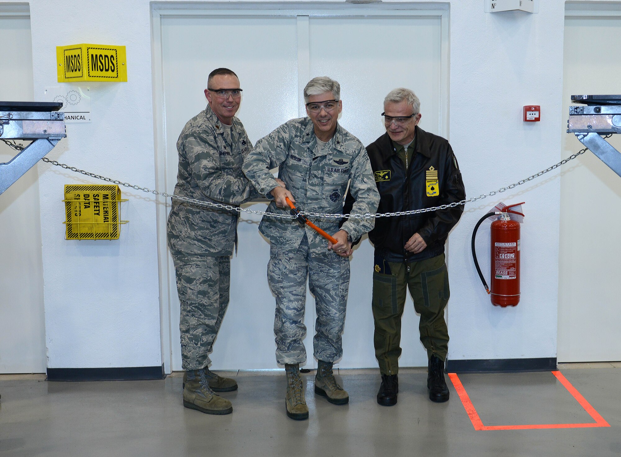 U.S. Air Force Maj. Franklyn Shepherd, 31st Maintenance Squadron commander, Brig. Gen. Barre Seguin, 31st Fighter Wing commander and Col. Valentino Savoldi, Pagliano e Gori Airport commander, cut a chain during the grand opening of the new aerospace ground equipment building, March 16, 2015, at Aviano Air Base, Italy. The new building provides an improved work center for 31 MXS Airmen and a central hub for more than 600 pieces of equipment.  (U.S. Air Force photo by Airman 1st Class Deana Heitzman/Released)