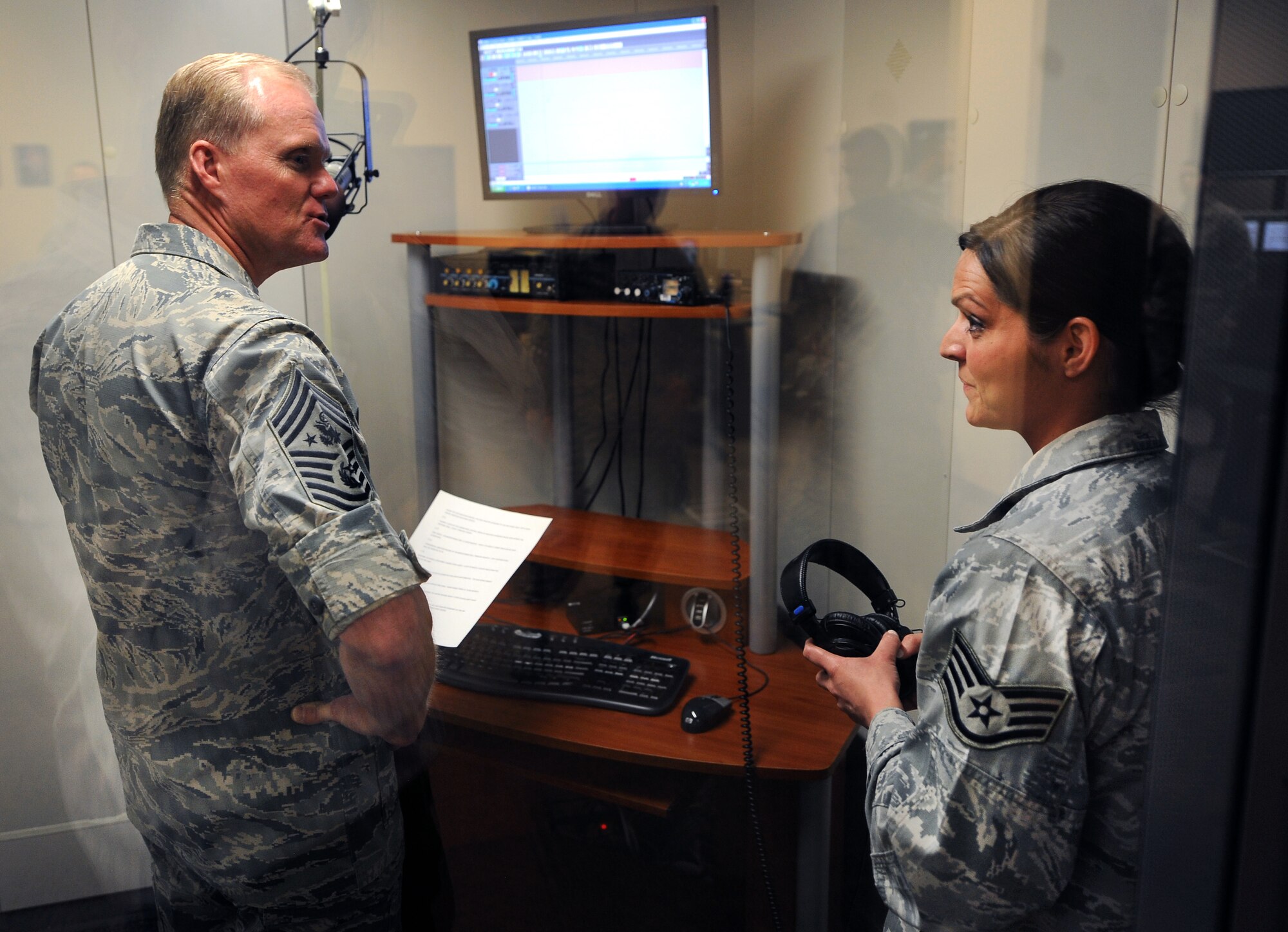 Chief Master Sgt. of the Air Force James Cody receives instruction from U.S. Air Force Staff Sgt. Laura Mickus, American Forces Network weather broadcaster, on how to record the forecast from inside a sound booth at the Air Force Weather Agency March 11, Offutt Air Force Base, Neb. The unit produces a two and four-day forecast for its more than 1.5 million viewers worldwide. (U.S. Air Force photo by Josh Plueger)