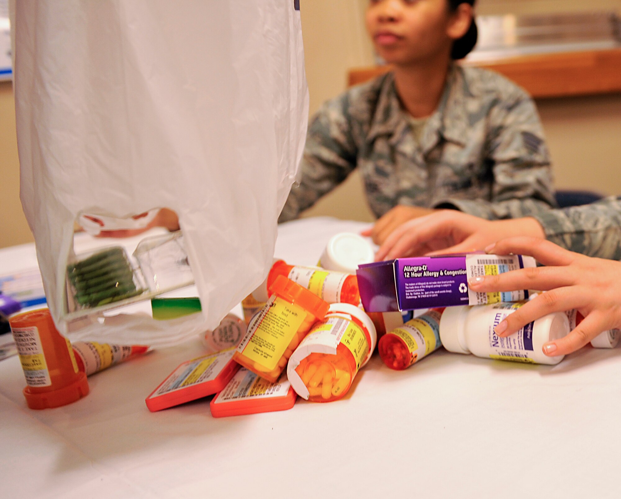 A customer drops prescription medication onto a table at the 18th Medical Group during the Drug Take-Back Day event on Kadena Air Base, Japan, March 12, 2015. The 18th Security Forces Squadron and 18th Medical Group Pharmacy conducted Drug Take-Back Day to give all active duty service members and their families, civilian employees and retirees an opportunity to turn in expired, unused and unwanted prescription and over-the-counter medications. (U.S. Air Force photo by Naoto Anazawa)