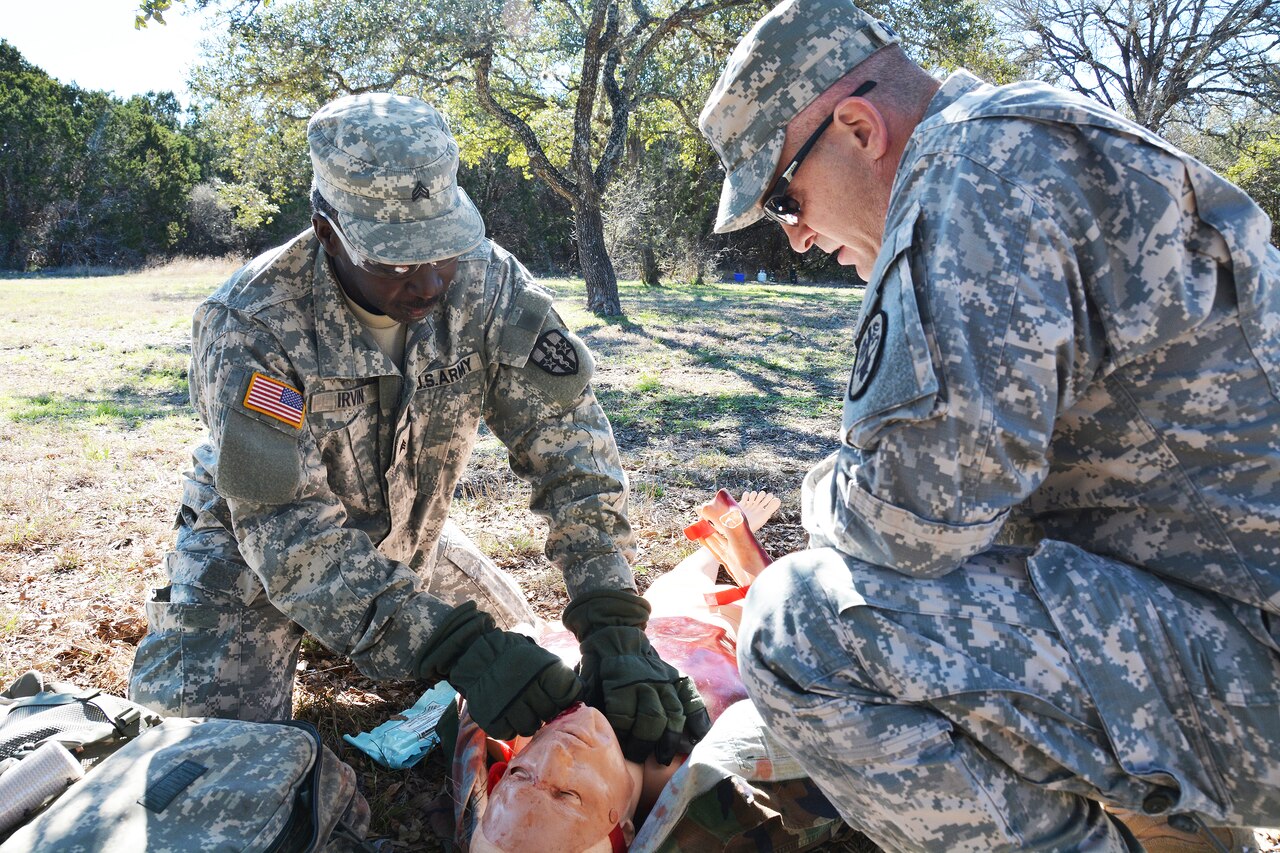 Army Sgt. Rashaid Irvin, left, treats a simulated casualty Feb. 18, 2015, at Camp Bullis, Texas, as part of the Joint Emergency Medical Technician Sustainment Training field validation, as Army Staff Sgt. Brian Cummings, noncommissioned officer in charge of the course, looks on. Courtesy photo by Robert Shields