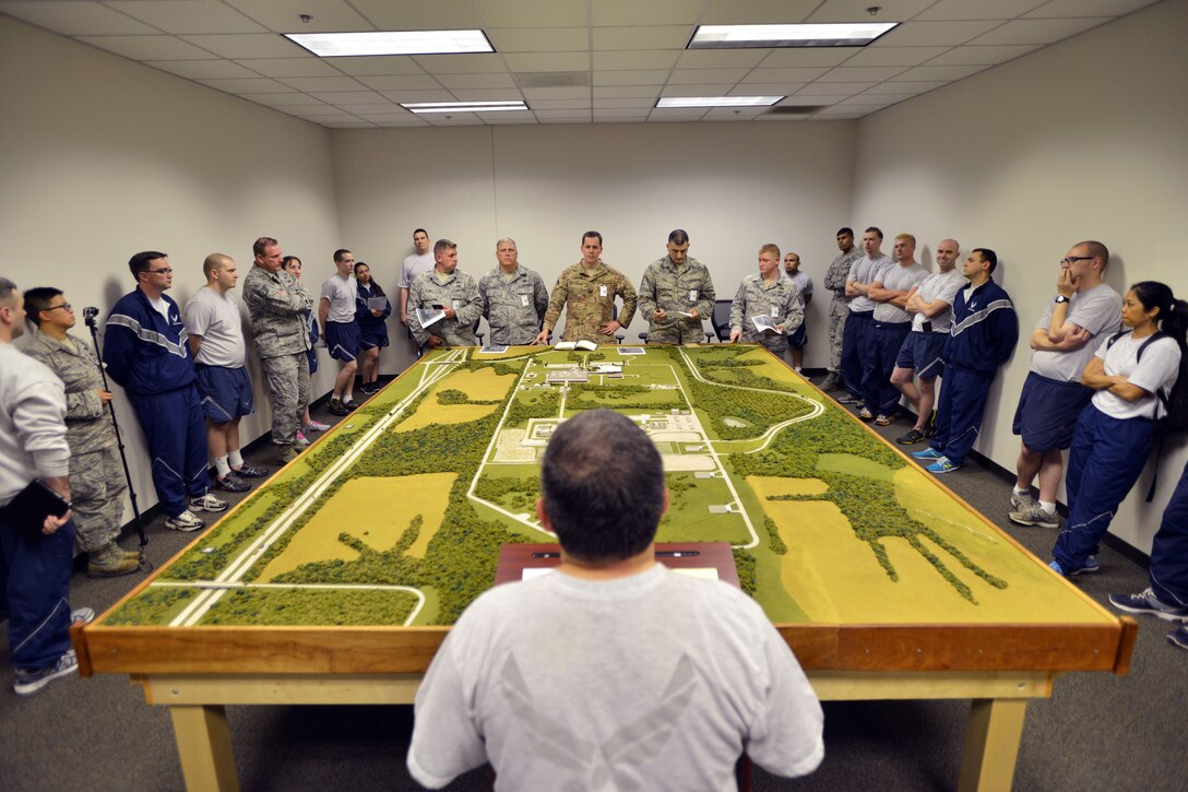 Air Force Senior Master Sgt. David Perez, foreground, conducts the student portion of a mission briefing at the emergency operations center during Global Dragon Deployment in Perry, Ga., March 13, 2015. Perez is an emergency manager assigned to the Oklahoma National Guard's 137th Refueling Wing. The three-day mission provides a refresher course for airmen, allowing them to put their skills to use to identify live chemical, biological, radiological and nuclear agents and materials.