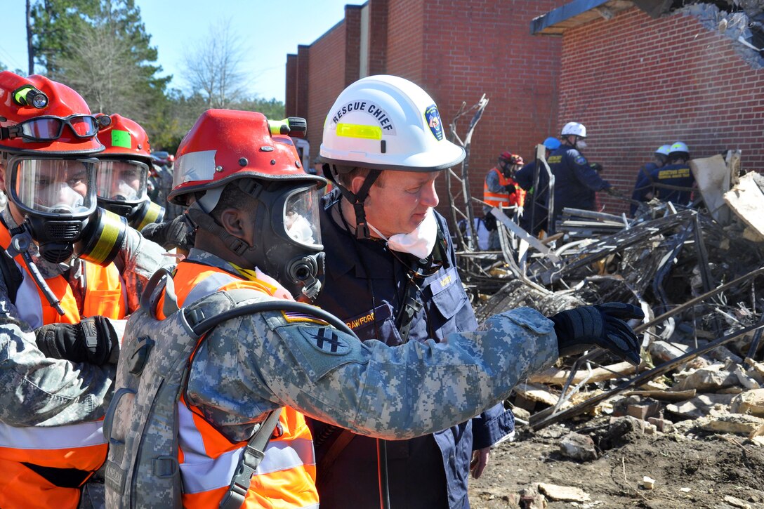 Army Staff Sgt. Gary Johnson, foreground, and Jim Payne, rescue chief with a tactical rescue team evaluate a simulated collapsed building site during Vigilant Guard South Carolina in Georgetown, S.C., March 8, 2015. 