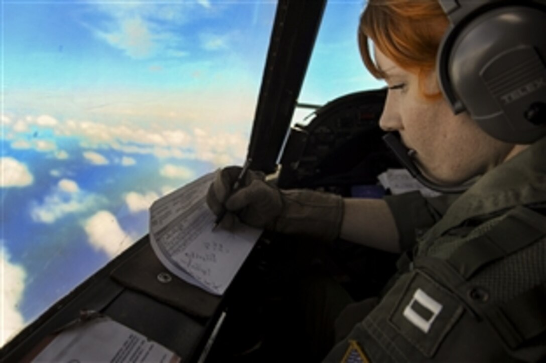 Navy Lt. Emily Cordle writes down communication frequencies during a torpedo exercise as part of her squadron’s advanced readiness program near Kaneohe Bay, Hawaii, March 6, 2015. Cordle is assigned to Patrol Squadron 9.