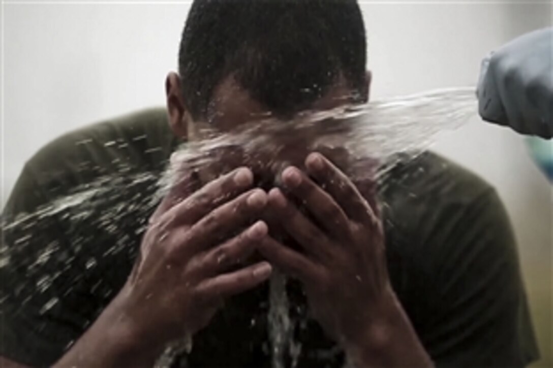 A U.S. Marine splashes water in his eyes during training with oleoresin capsicum, commonly known as pepper spray, in Okinawa, Japan, March 6, 2015. Marines assigned to the security augment force on Marine Corps Air Station Futenma participated in an endurance course while exposed to the spray to gain a better understanding of the nonlethal weapon’s effects. 
