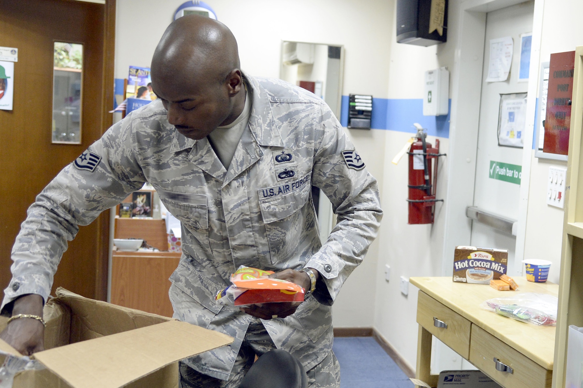 Staff Sgt. Terrell, NCO in-charge readiness and resources, unpacks a care package at an undisclosed location in Southwest Asia Mar. 11, 2015. Aside from giving out free food and snacks, the chapel also has Operation Home Front, which allows individuals to skype or FaceTime home to their families for various life events. Terrell is currently deployed from Seymour Johnson Air Force Base, N.C., and is a native of Bath, N.C. (U.S. Air Force photo/Tech. Sgt. Marie Brown)