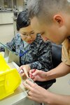 U.S. Air Force Staff Sgt. Justin Rhodes (right), 18th Dental Squadron dental lab craftsman, shows Japan Air Self-Defense Force Tech. Sgt. Emi Takahashi, left, SDF Naha Hospital dental lab technician, how an acrylic tooth should fit in the mouth of a patient during an NCO exchange on Kadena Air Base, Japan, March 4, 2015. Rhodes showed Takahashi new technology that her lab doesn’t have and gave her ideas on how to make her shop more effective. (U.S. Air Force photo by Staff Sgt. Marcus Morris)
