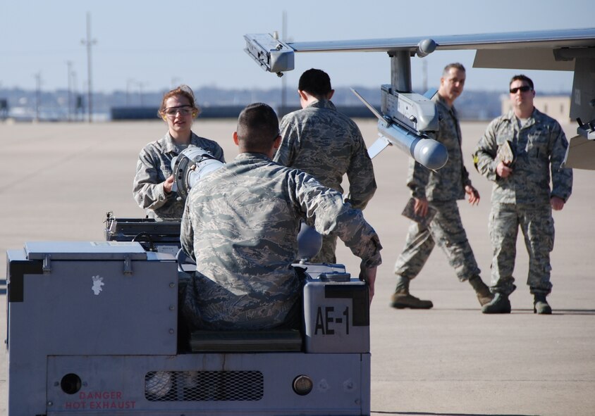 NAVAL AIR STATION FORT WORTH JOINT RESERVE BASE, Texas - 301st Aircraft Maintenance Unit Airmen pull up to the aircraft with inert munitions Feb. 8 during the annual weapons load competition here. Working side-by-side, active duty and Reserve Airmen towed, placed, and properly loaded four inert munitions onto each of the four F-16s in under 47 minutes. Three inspectors evaluated a crew on general knowledge test and munitions load. (U.S. Air Force photo/Staff Sgt. Melissa Harvey)