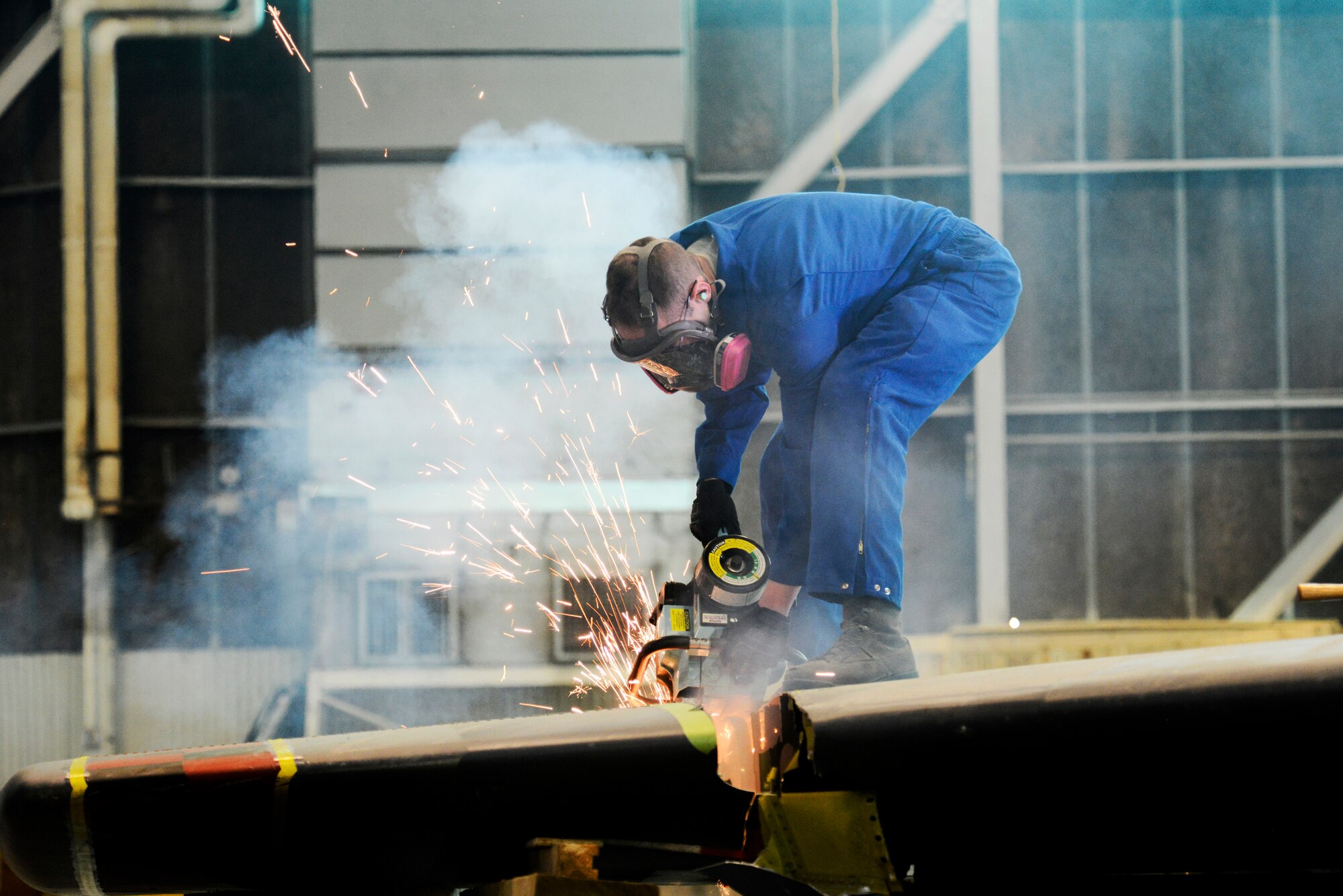 An Airman from the 5th Maintenance Squadron repair and reclamation section uses an electric saw to cut the vertical fin of a B-52H Stratofortress on Minot Air Force Base, N.D., Feb. 25, 2015. The fin is being cut for shipping purposes for thermal and blast testing. Thermal testing will look at the thermal response of coatings and material stack-ups to a pulse similar to a nuclear thermal pulse. Blast testing will be conducted at a future date looking into the structural response to an overpressure shockwave. The results will be used to update the nuclear hardness of the aircraft, which is used in models to produce Escape Distance Required Curves within Technical Order 25s. (U.S. Air Force photo/Senior Airman Brittany Y. Bateman)