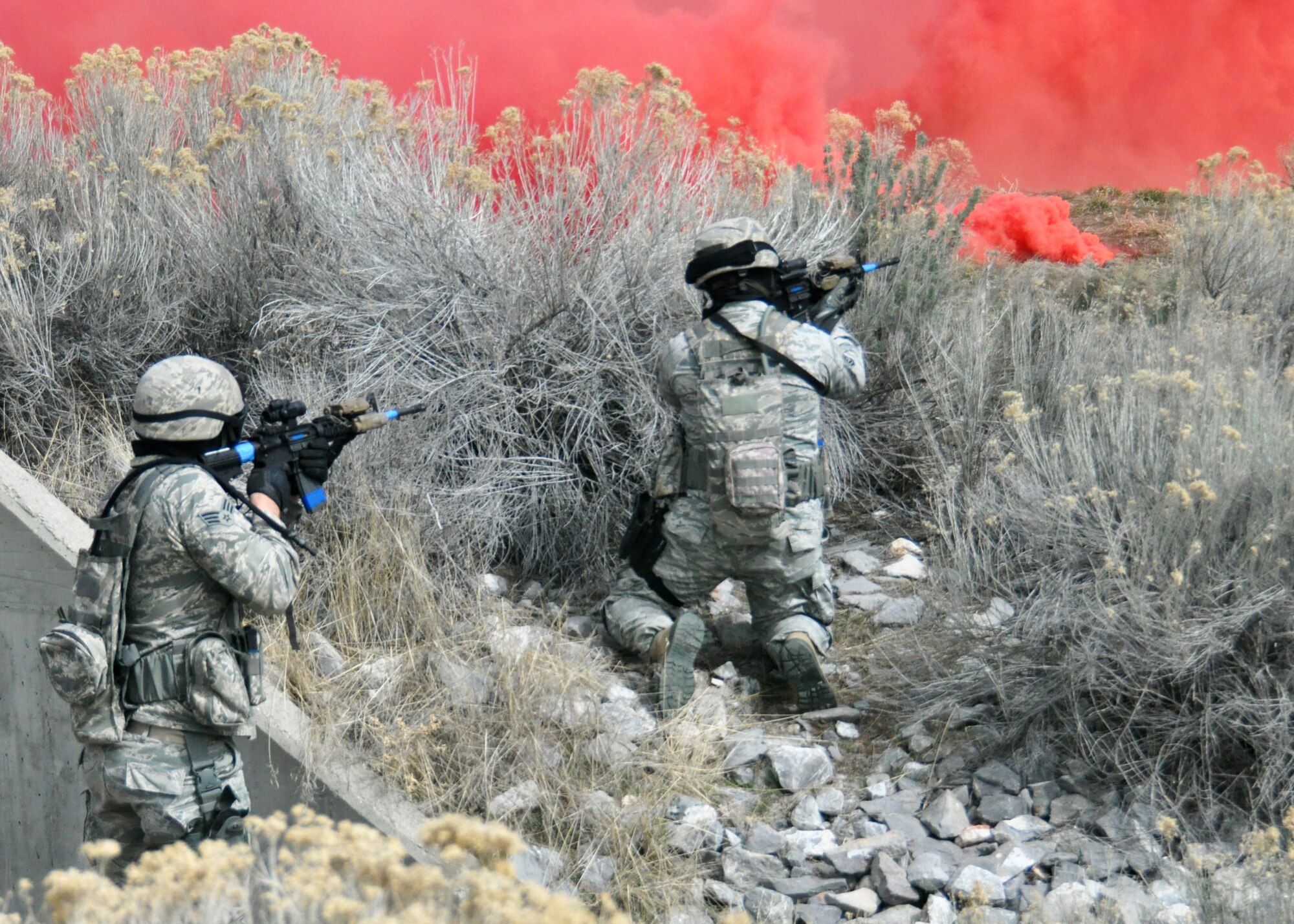 Senior Airman Bodie Bowthorpe and Tech. Sgt. Nicholas Lemonds, 419th Security Force Squadron, fire back at enemy targets through a screen of red smoke while other team members enter and take control of a building. More than 50 reservists from the 419th Fighter Wing participated in the four-day training exercise at Camp Williams March 11-14. (U.S. Air Force photo/Staff Sgt. Crystal Charriere)