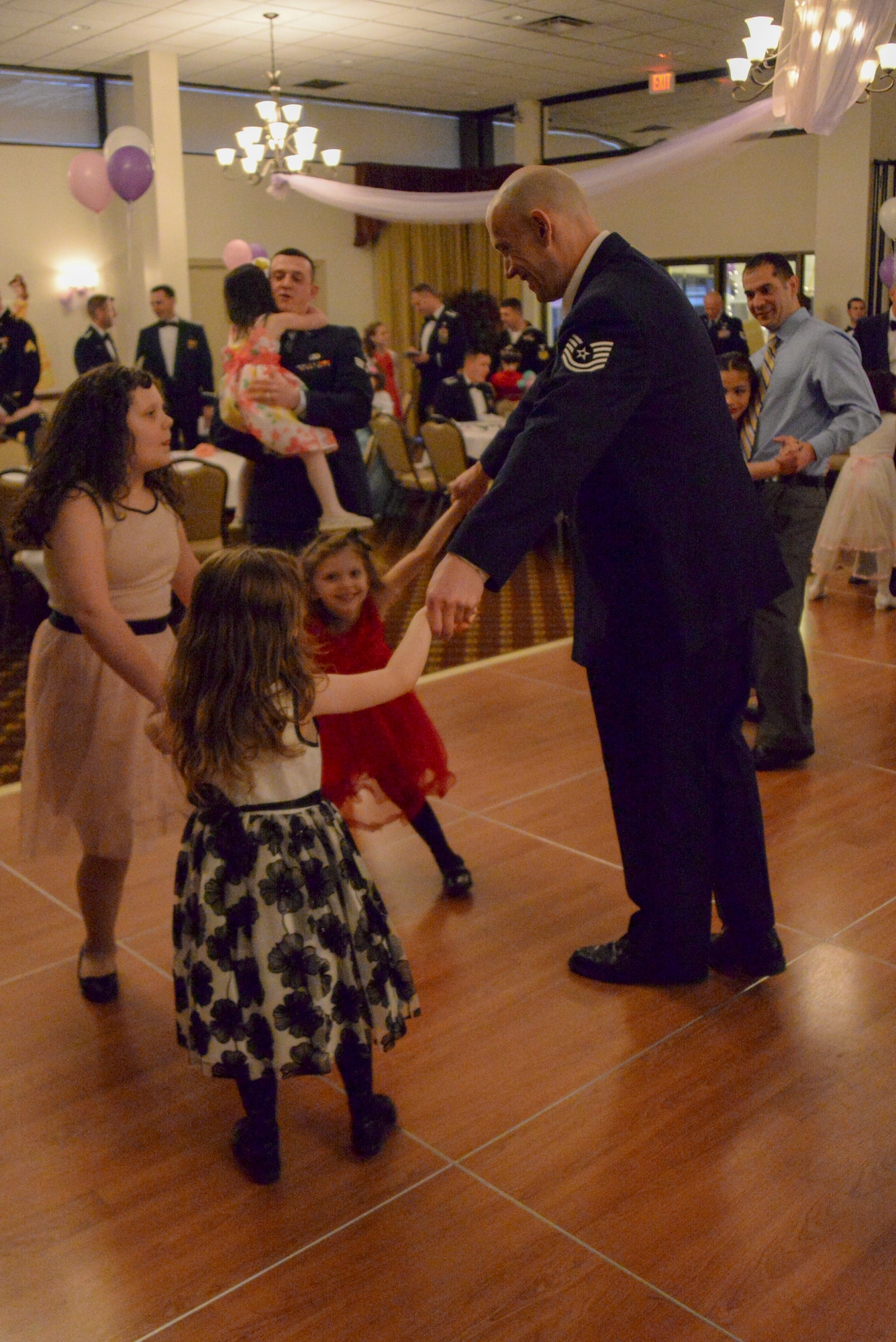 A father with three daughters makes sure they all share a dance during the Annual Princess and Her Hero Dance at Tommy B’s Community Activities Center on Joint Base McGuire-Dix-Lakehurst, N.J., March 13, 2015. The dance is held each year for young girls and their fathers to share a special evening together, while showing young girls a positive male role model. (U.S. Air Force photo by Airman 1st Class Tara A. Williamson/Released)