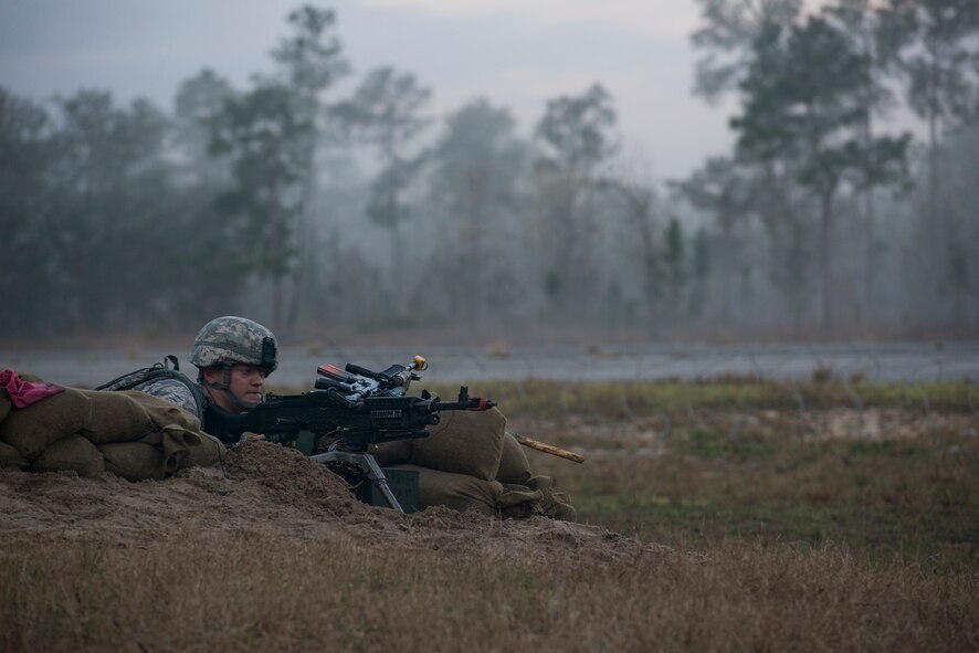 U.S. Air Force Airman 1st Class Jacob Gorter, 105th Security Forces Squadron, adjusts an M240B machine gun while building up his defensive fighting positing during a mission readiness exercise March 11, 2015, at Camp Blanding, Fla. After arriving at a new forward operating base, Airmen slowly improve the DFPs to increase base security. (U.S. Air Force Photo by Senior Airman Ryan Callaghan/Released)
