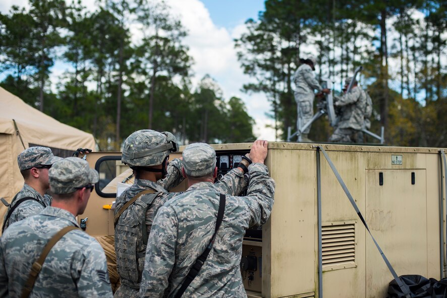 Airmen from the 824th Base Defense Squadron set up an ECU, front, and a satellite terminal during a mission readiness exercise March 10, 2015, at Camp Blanding, Fla. Defenders begin setting up the base defense operations center, a medical tent, and sleeping tents after the location has been secured. (U.S. Air Force Photo by Senior Airman Ryan Callaghan/Released)
