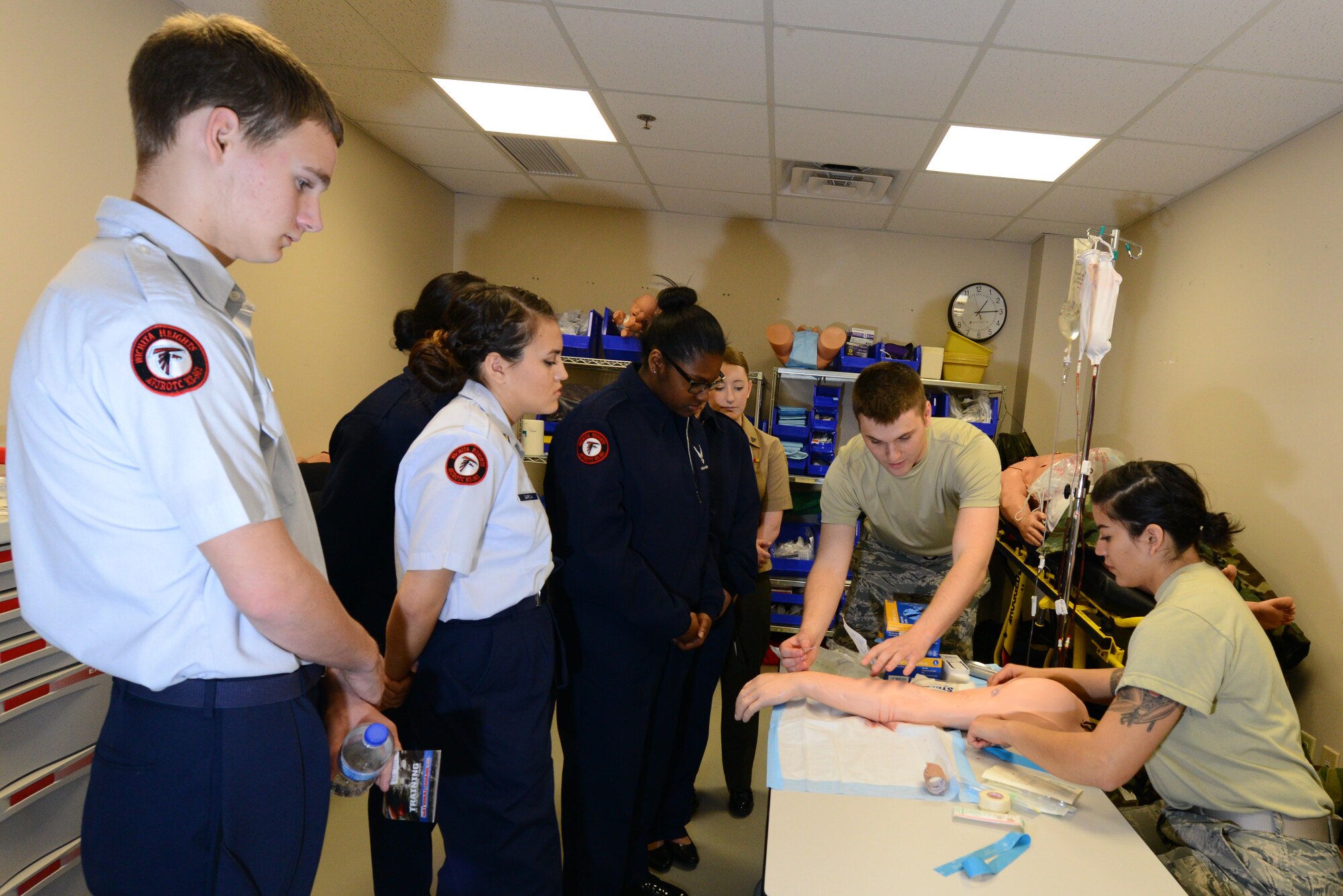 Airmen 1st Class Jordon Jeans, second from right, and Chrystal Visser, 22nd Medical Operations Squadron medical technicians, demonstrate to a group of Junior ROTC cadets how to give a patient an IV March 11, 2015, at McConnell Air Force Base, Kan. Cadets from local schools visited McConnell to learn about different careers available in the Air Force. (U.S. Air Force photo by Airman 1st Class Christopher Thornbury)