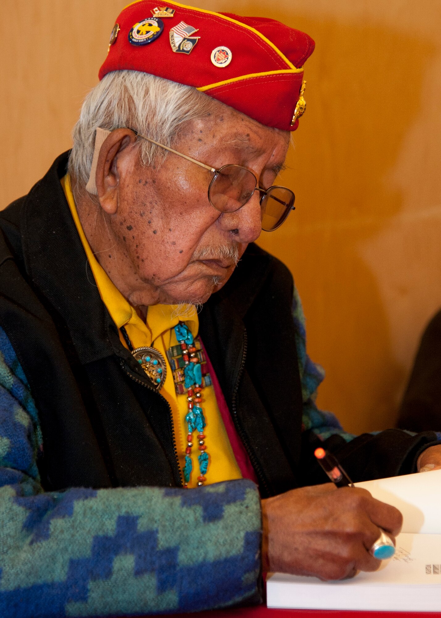 PETERSON AIR FORCE BASE, Colo. -- Bill Toledo, former Marine Navajo Code Talker, signs a book during a fundraising event at the Peterson AFB Base Exchange March 12. Of the more than 400 original Code Talkers who served during World War II, Toledo is one of 20 still alive today. The Navajo language had few words for military equipment, so Code Talkers often described aircraft as different types of birds and ships as different types of fish. (U.S. Air Force photo/Staff Sgt. J. Aaron Breeden)