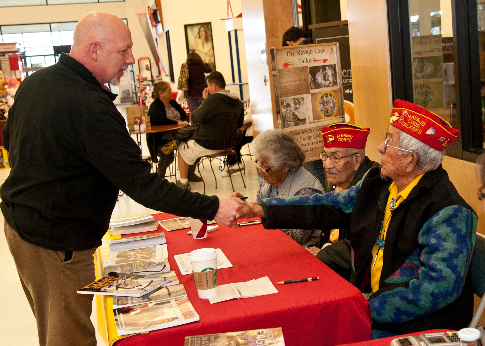 PETERSON AIR FORCE BASE, Colo. -- Scot Brelend (left), retired Marine, shakes the hand of Bill Toledo (right), former Marine Navajo Code Talker, during a fundraising event at the Peterson AFB Base Exchange March 12. Of the more than 400 original Code Talkers who served during World War II, Newman is one of 20 Code Talkers still alive today. The Navajo language had few words for military equipment, so Code Talkers often described aircraft as different types of birds and ships as different types of fish. (U.S. Air Force photo by Staff Sgt. J. Aaron Breeden)