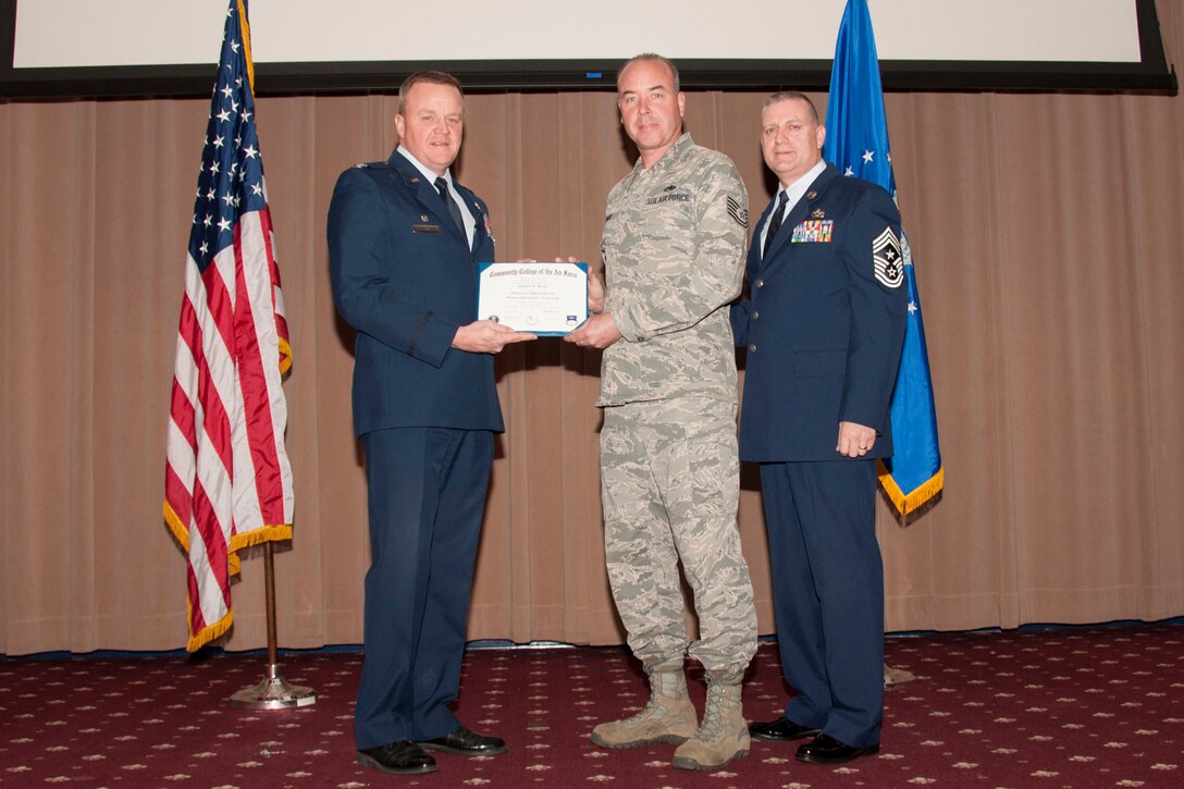 U.S. Air Force Col. Bruce Cox, 307th Bomb Wing commander, presents TSgt Stephen Sorge, 307th Maintenance Squadron his degree from the Community College of the Air Force in Aviation Maintenance Technology, March 8, 2015, Barksdale Air Force Base, La. (U.S. Air Force photo by Tech. Sgt. Theodore Daigle/Released)