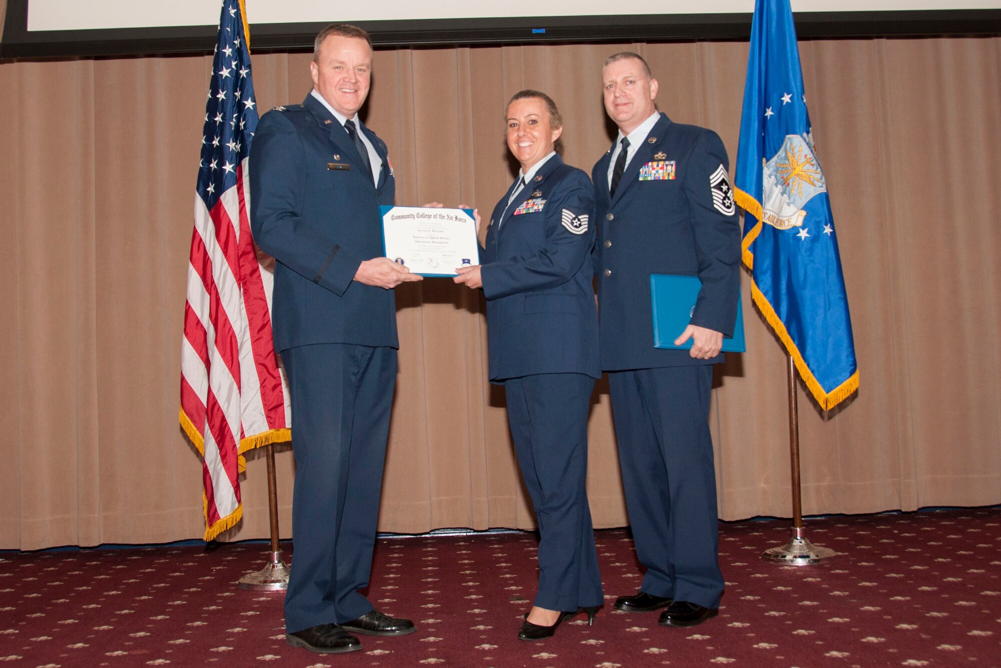 U.S. Air Force Col. Bruce Cox, 307th Bomb Wing commander, presents TSgt Teresa L. Broxson, 307th Force Support Squadron two degrees from the Community College of the Air Force, her 1st in Information Management and the second in Education & Training Management, March 8, 2015, Barksdale Air Force Base, La. (U.S. Air Force photo by Tech. Sgt. Theodore Daigle/Released)