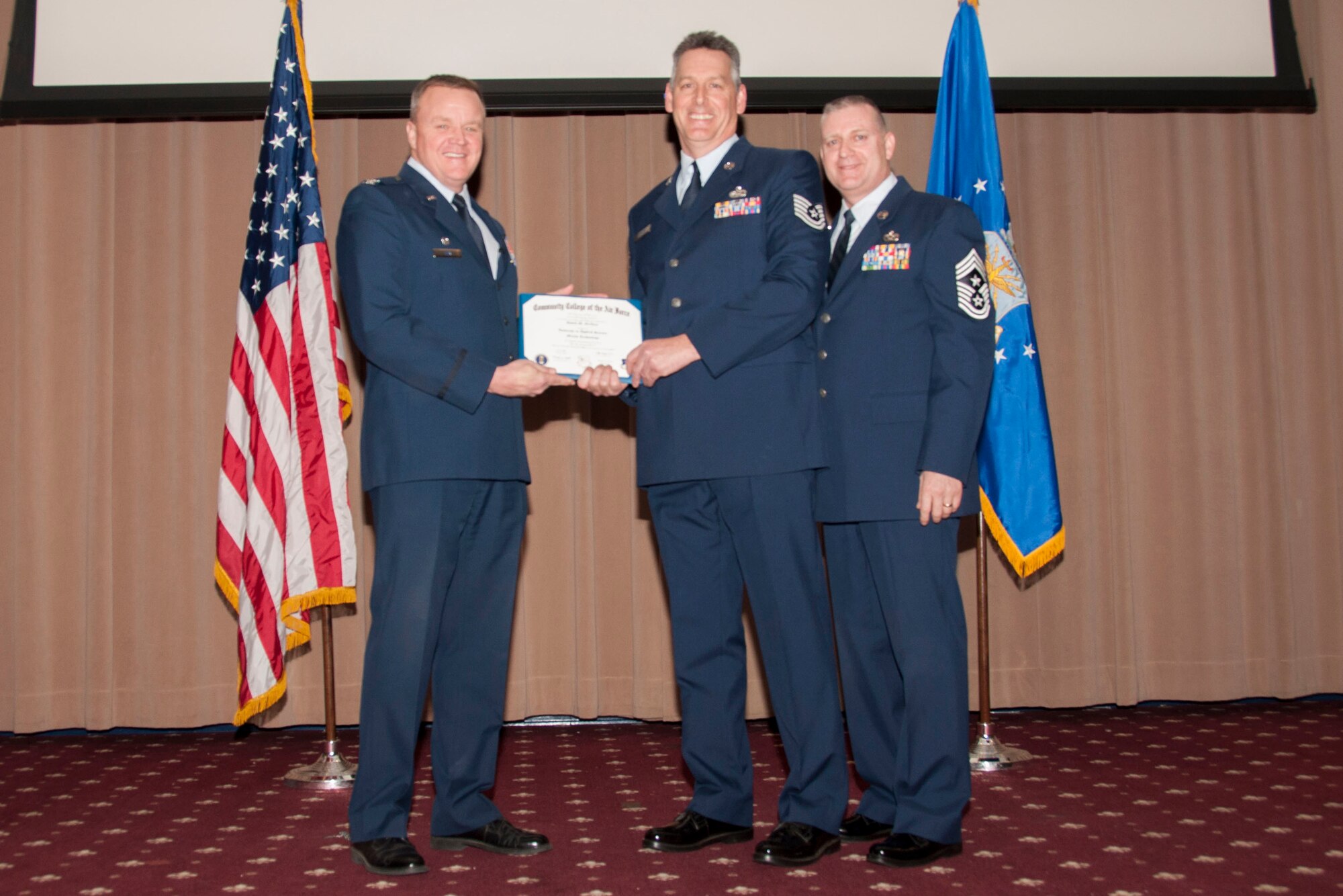 U.S. Air Force Col. Bruce Cox, 307th Bomb Wing commander, presents TSgt David M. Griffore of the 307th Maintenance Squadron his degree from the Community College of the Air Force in Metals Technology, March 8, 2015, Barksdale Air Force Base, La. (U.S. Air Force photo by Tech. Sgt. Theodore Daigle/Released)