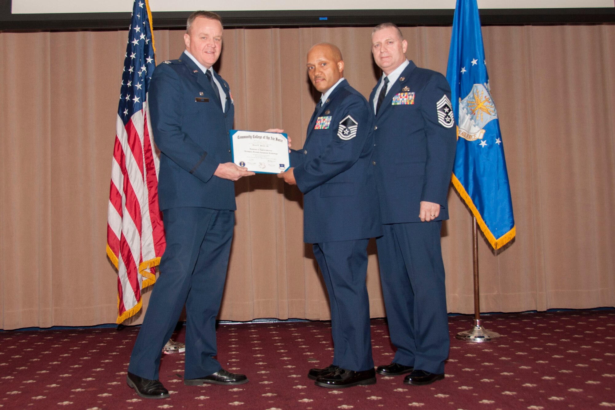 U.S. Air Force Col. Bruce Cox, 307th Bomb Wing commander, presents MSgt Jerry L. Porter of the 307th Maintenance Squadron his degree from the Community College of the Air Force in Aerospace Ground Equipment Technology, March 8, 2015, Barksdale Air Force Base, La. (U.S. Air Force photo by Tech. Sgt. Theodore Daigle/Released)