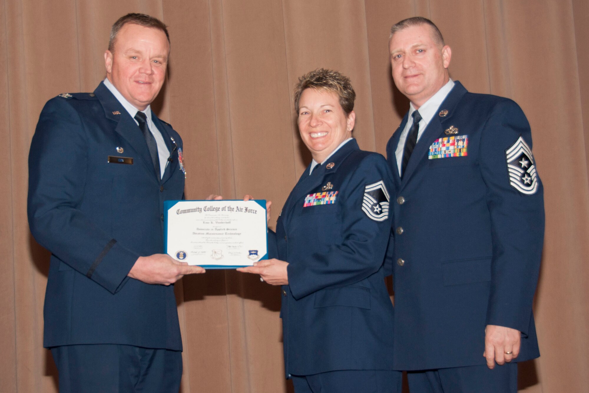 U.S. Air Force Col. Bruce Cox, 307th Bomb Wing commander, presents SMSgt Lisa Vanderhoff, 307th Maintenance Squadron, her degree from the Community College of the Air Force in Aviation Maintenance Technology, March 8, 2015, Barksdale Air Force Base, La.  (U.S. Air Force photo by Tech. Sgt. Theodore Daigle/Released)