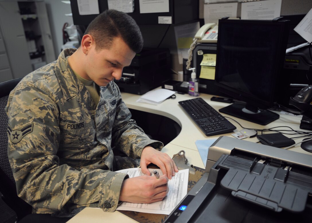 Airman 1st Class Jacob Pounds, 11th Force Support Squadron customer service technician, completes a customer's request for a new ID card on Joint Base Andrews, MD, March 16, 2015,. The Military Personnel Flight recently began prioritizing military members needing new Common Access Cards during lunch hours Monday and Friday to greatly reduce the wait time for uniform wearers while also reducing overall wait time. (U.S. Air Force photo/Senior Airman Preston Webb)