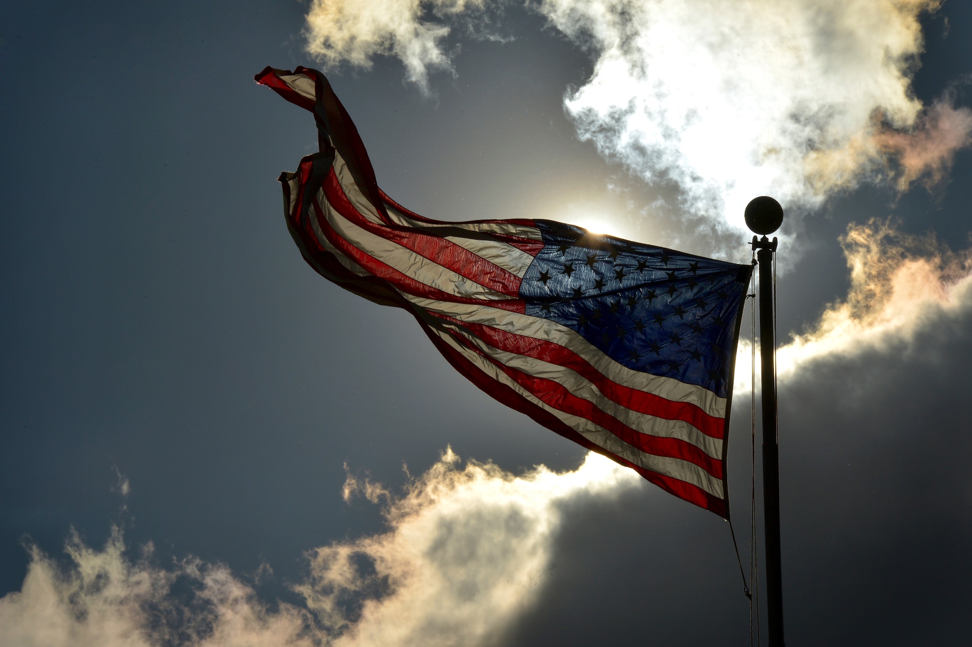 The U.S. flag is illuminated by the sun as it's flown over a Defense Department military installation June 5, 2014. As election season begins in the months to come, it's important to take note of the restrictions placed upon military and Defense Department civilian political activity. (U.S. Air Force photo by Staff Sgt. Kenny Holston)