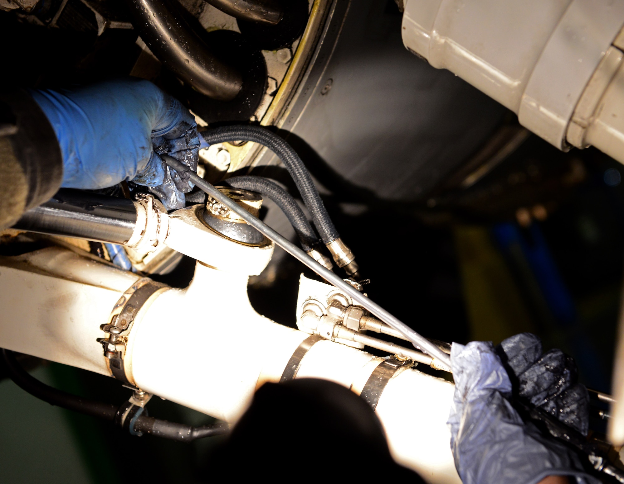 U.S. Air Force crew chiefs from the 31st Aircraft Maintenance Squadron work together while lubing a pivot point underneath an F-16 Fighting Falcon after washing the aircraft, March 17, 2015, at Aviano Air Base, Italy. Washing an aircraft takes approximately 4 to 6 hours for a minimum of three crew chiefs. (U.S. Air Force photo by Senior Airman Matthew Lotz/Released)