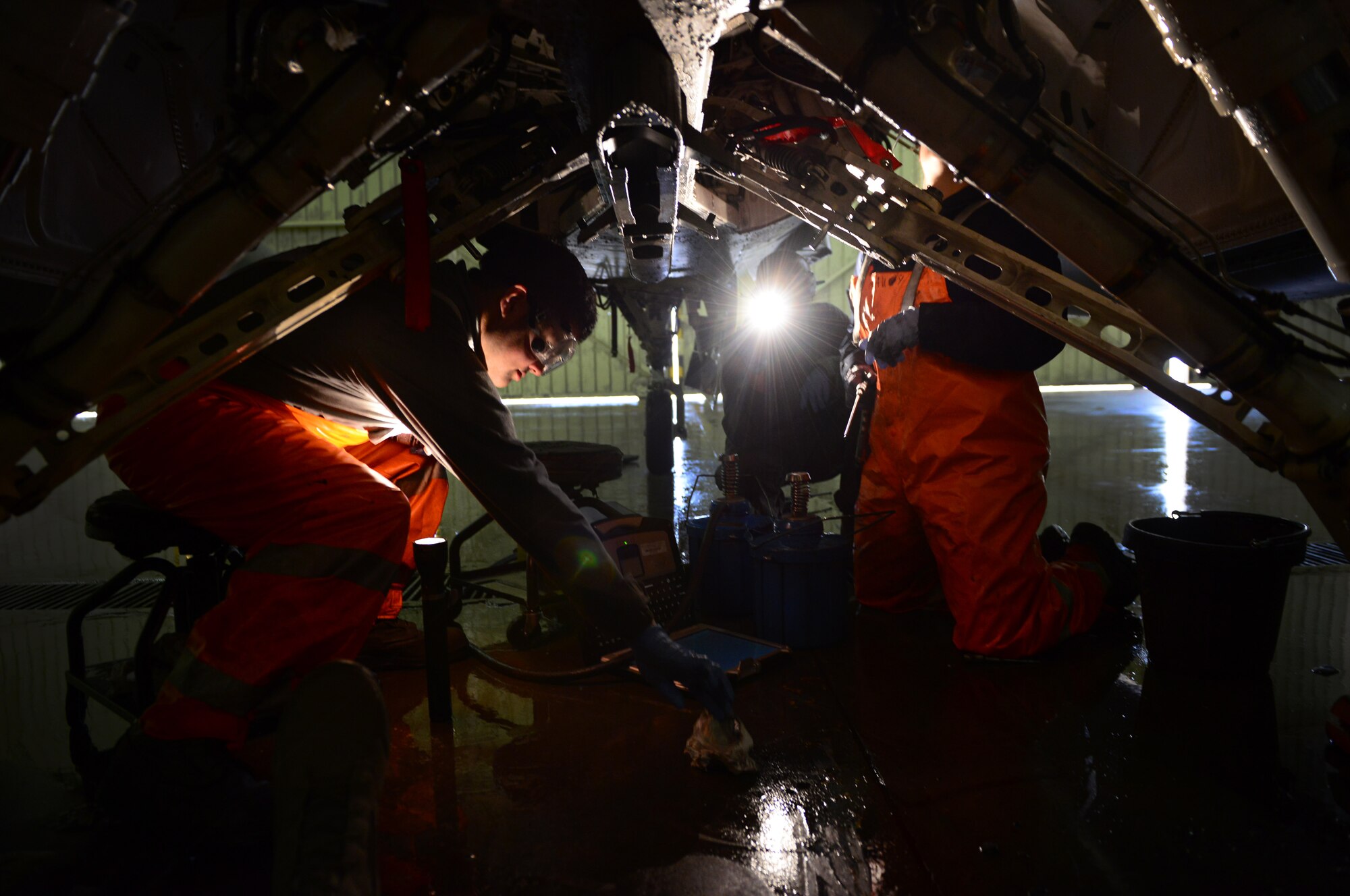 U.S. Air Force crew chiefs from the 31st Aircraft Maintenance Squadron lube pivot points underneath an F-16 Fighting Falcon after washing the aircraft, March 17, 2015, at Aviano Air Base, Italy. To assist with crew chiefs’ frequent inspections, Aviano aircraft receive a thorough cleaning using soap, water and lube every 180 days. (U.S. Air Force photo by Senior Airman Matthew Lotz/Released)