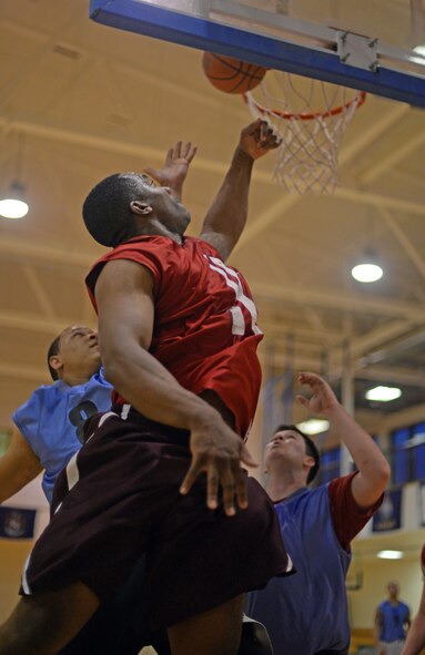 U.S. Air Force Staff Sgt. Steven McCoy, center, 100th Logistics Readiness Squadron NCO in charge of inbound receiving from Columbia, Ohio, blocks a layup from U.S. Air Force Staff Sgt. Lionel Morris, left, 100th Civil Engineer Squadron electrical systems craftsman from Philadelphia, March 12, 2015, during a basketball championship game, at the Hardstand Fitness Center on RAF Mildenhall, England. The 100th CES won against 100th LRS 67-53.   (U.S. Air Force photo by Senior Airman Christine Griffiths/Released)