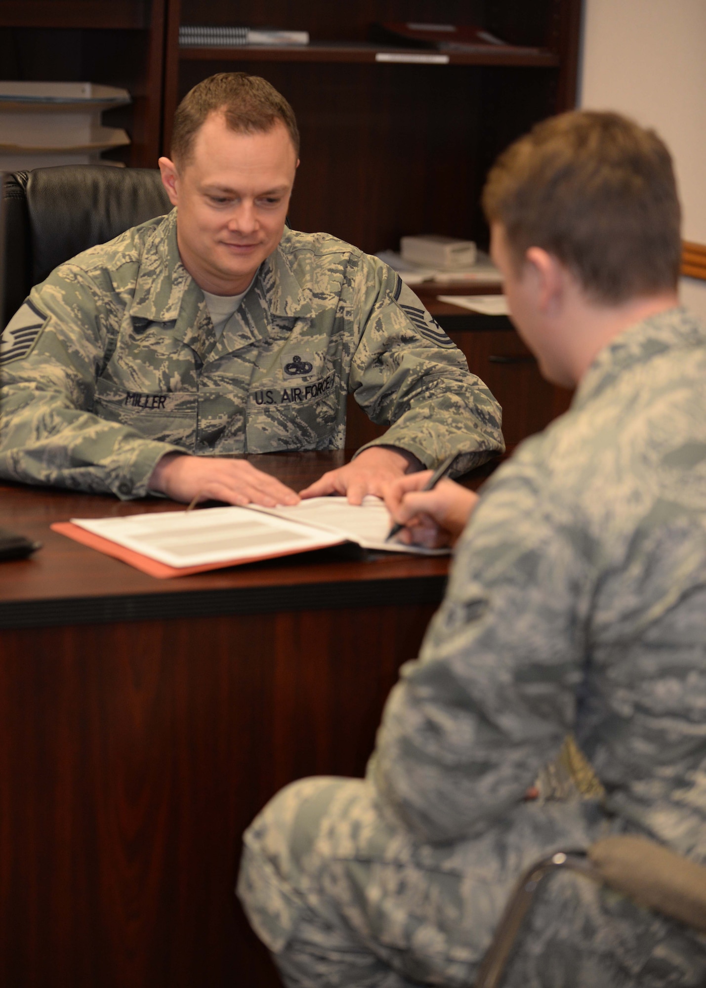 Airman 1st Class Matthew Gallagher, 28th MXS avionics test station technician, reviews his mobility folder with Master Sgt. Matthew Miller, 28th Maintenance Squadron unit deployment manager, at Ellsworth Air Force Base, S.D., March 4, 2015. UDMs ensure squadron personnel have necessary deployment items and inform leadership of the unit’s deployment status. (U.S. Air Force photo by Airman 1st Class Rebecca Imwalle/Released)