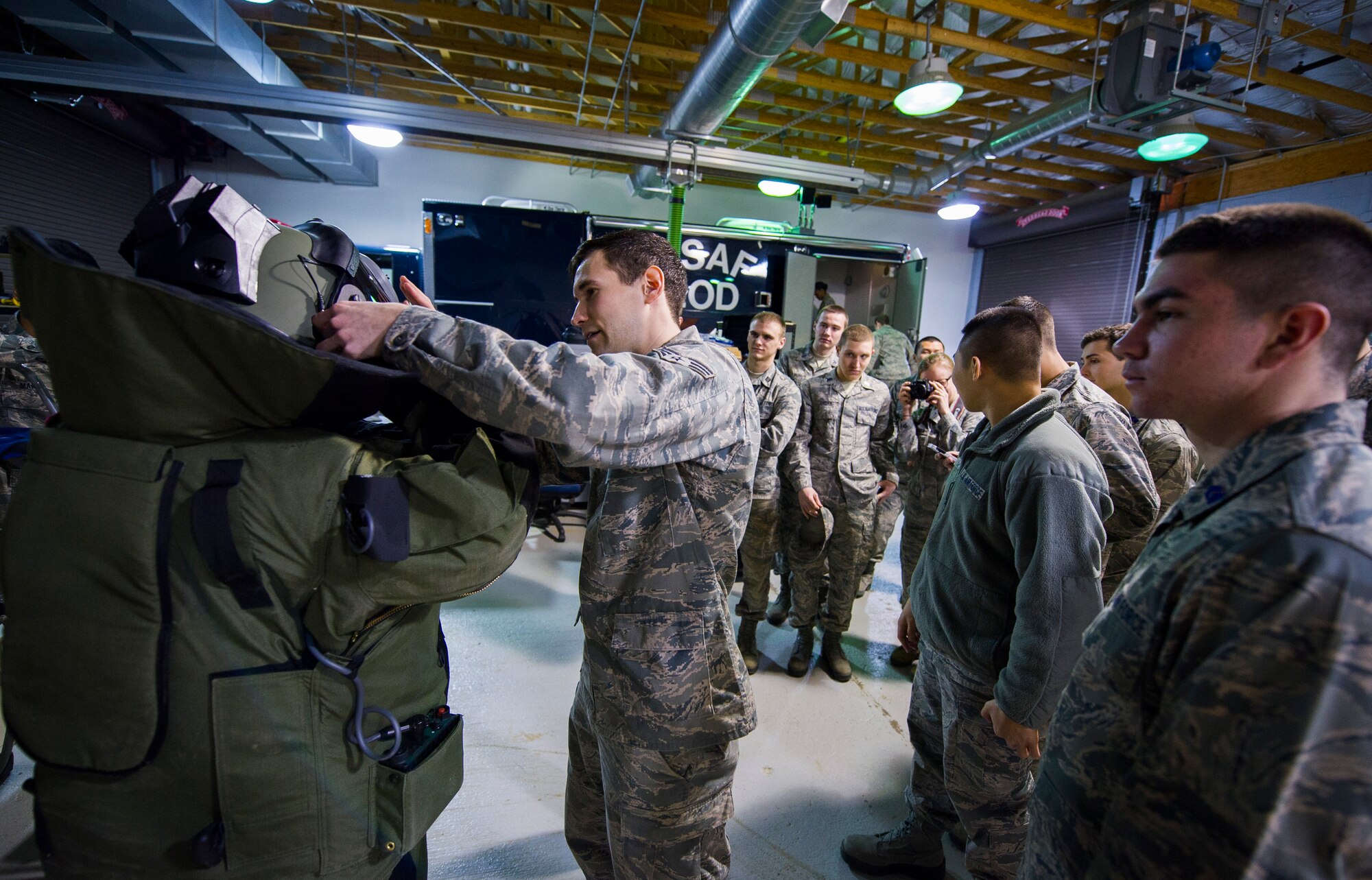 Senior Airman Richard Mirabal, 11th Civil Engineer Squadron explosive ordnance disposal technician, assists a Reserve Officers' Training Corps cadet in putting on an EOD-9 bomb suit at Joint Base Andrews, Md., March 16, 2015. The EOD-9 bomb suit weighs approximately 60 pounds and is designed to withstand five pounds of C-4 explosives from five feet away. (U.S. Air Force photo/Staff Sgt. Chad C. Strohmeyer/Released)