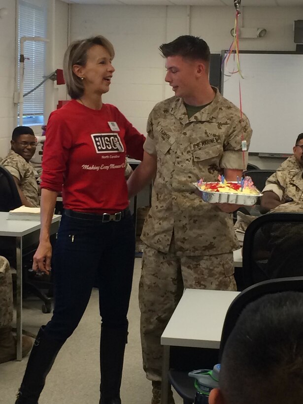 A representative from the Jacksonville USO presents PFC Taylor with a birthday cake and balloon.