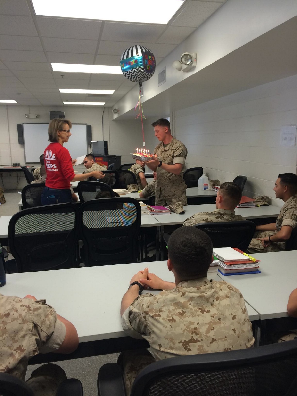 A representative from the Jacksonville USO presents PFC Taylor with a birthday cake and balloon.