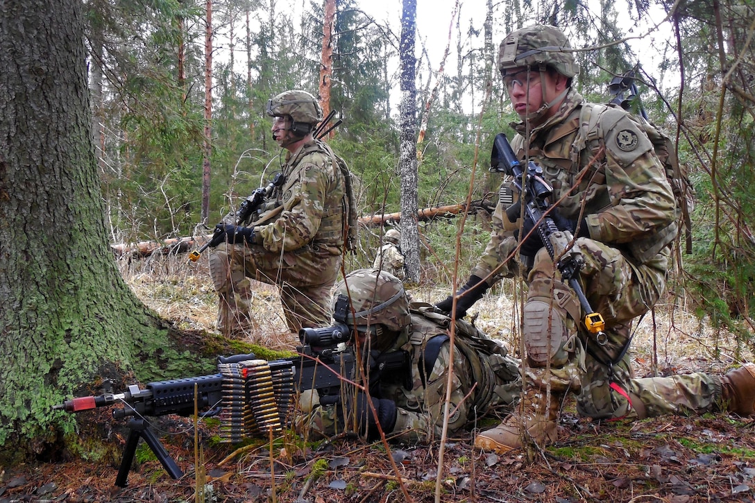 U.S. soldiers conduct a patrol halt while maneuvering through a forest ...