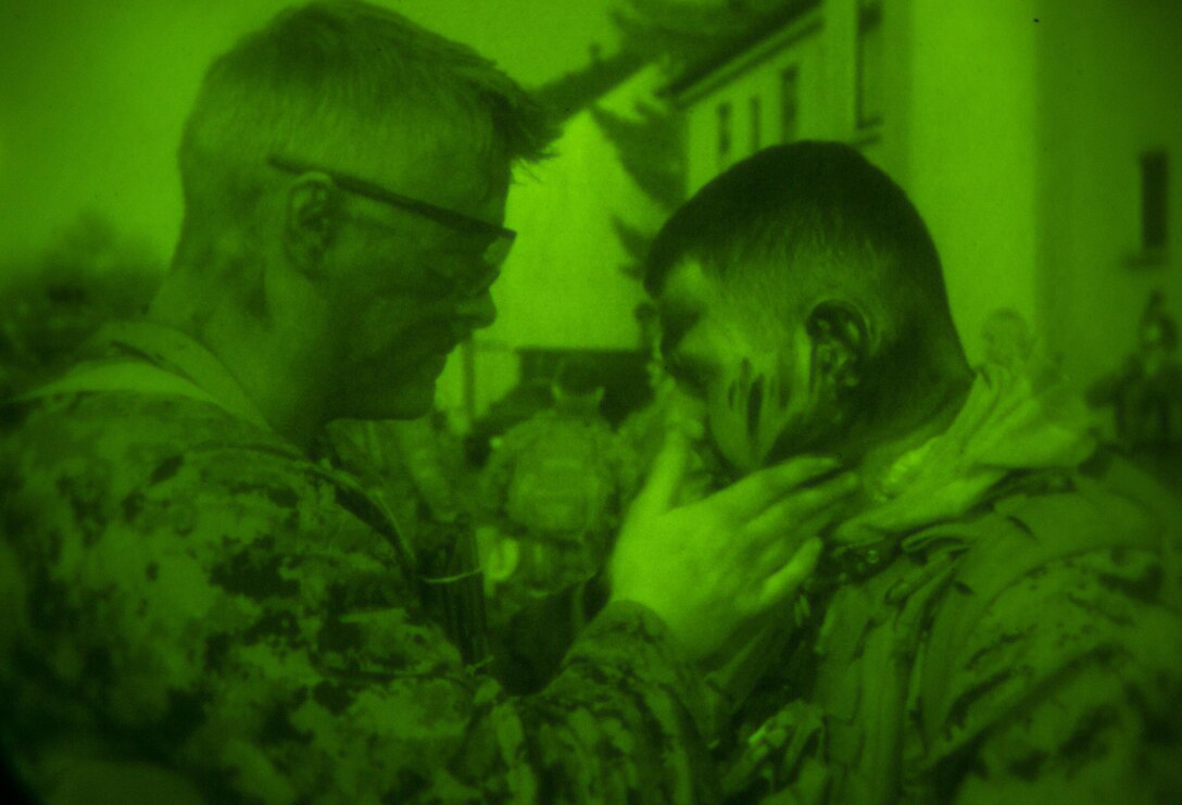 A U.S. Marine with Special-Purpose Marine Air-Ground Task Force Crisis Response-Africa dons camouflage paint before embarking on a joint night raid during training with Army Special Forces in Baumholder, Germany, March 11, 2015. The Marines slipped into a block of buildings under the cover of darkness and established a foothold for a precision strike by Special Forces personnel. (U.S. Marine Corps photo by Sgt. Paul Peterson/Released)