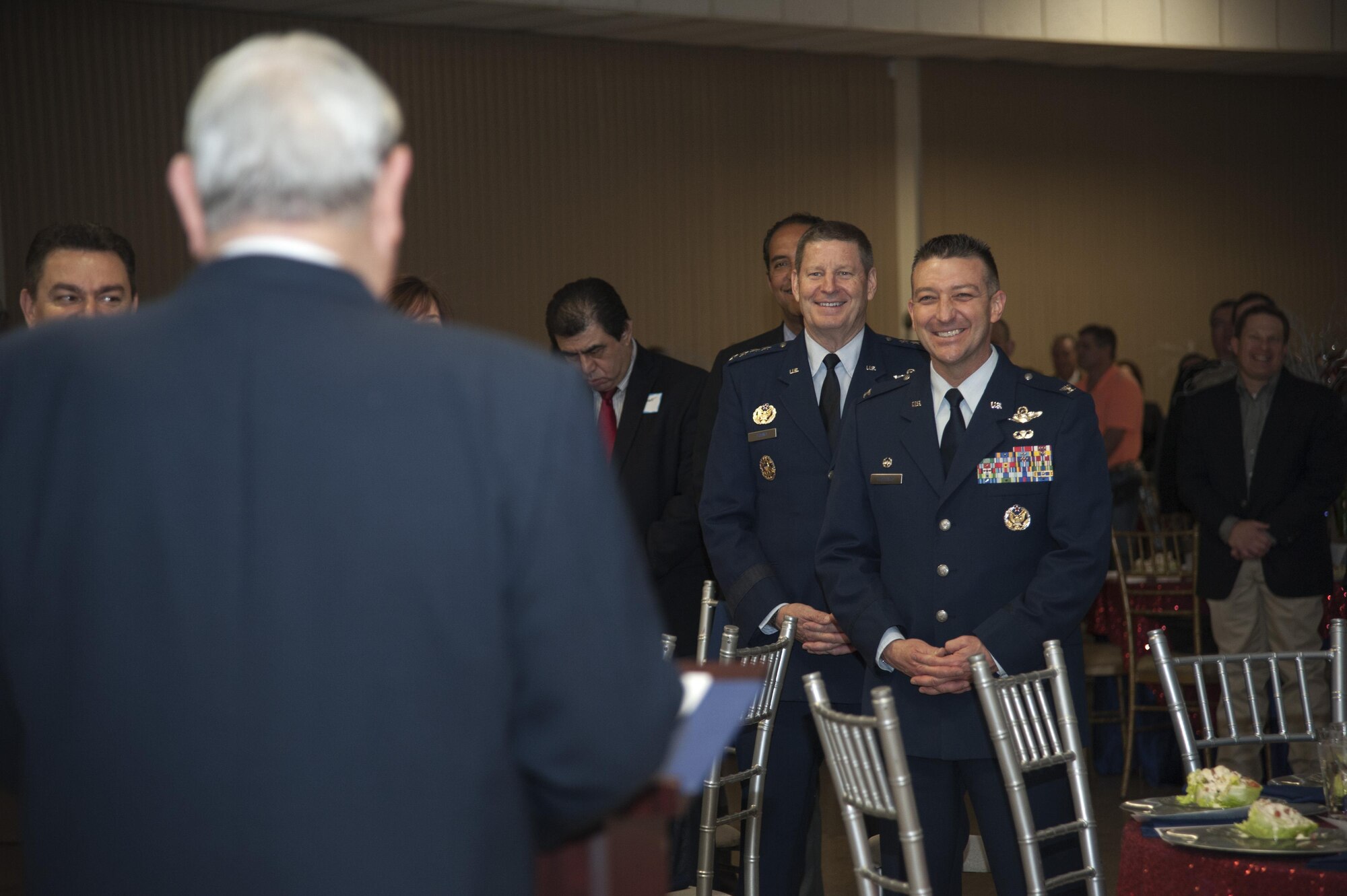 Gen. Robin Rand, commander of Air Education and Training Command, and Col. Brian Hastings, 47th Flying Training Wing commander, stand as retired Maj. Gen. Gerald Prather begins the evening's invocation at the Del Rio Annual Awards Banquet in Del Rio, Texas, March 12, 2015. Prather earned his pilot wings at Laughlin Air Force Base in 1956 and he has served the Del Rio community in a variety of positions since retiring. (U.S. Air Force photo by Staff Sgt. Nathan Maysonet)