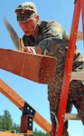 A member of a German combat engineer unit saws through a beam of an informational kiosk being constructed in the Black Hills National Forest on Victoria Lake Road June 19, 2010. The unit from Germany is teamed up with soldiers from the South Dakota Army National Guard's 155th Engineer Company during Golden Coyote, in conjunction with the Small Unit Exchange Program. The German unit will construct two kiosks before they depart for home June 26.