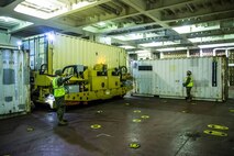 Marines carefully guide the Container-Lift and Maneuver System (C-LMS) between two containers during the Dense Pack Access Retrieval and Transit (DPART) Joint Capability Technology Demonstration (JCTD) Limited Operational Utility Assessment (LOUA) conducted aboard the SS Cape Island near Tacoma, WA