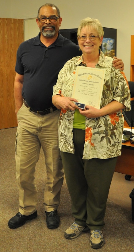 Cheri Magorno, multi-media specialist, accepts a Federal Length of Service Award for 20 years of service with the Department of Defense from her supervisor, Robert Jackson, public affairs officer, aboard Marine Corps Logistics Base Barstow, March 13.  Magorno has specialized in graphics with the Public Affairs Office here for the last 13 years. 