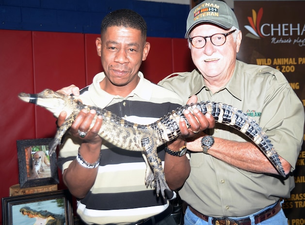 Angelo Knox, Equal Employment Opportunity Office, holds "Izzy Real," a 3-pound, roughly 3-year-old alligator, beside Tim Williams, Gatorland, Orlando, Fla., during Information, Tickets and Tours’ 17th Annual Travel and Recreation Trade Show aboard Marine Corps Logistics Base Albany, March 18. Thirty-four vendors from Georgia, Florida and Tennessee showcased theme parks, hotels, historical sites and more through a small alligator, brochures, pamphlets and souvenirs.