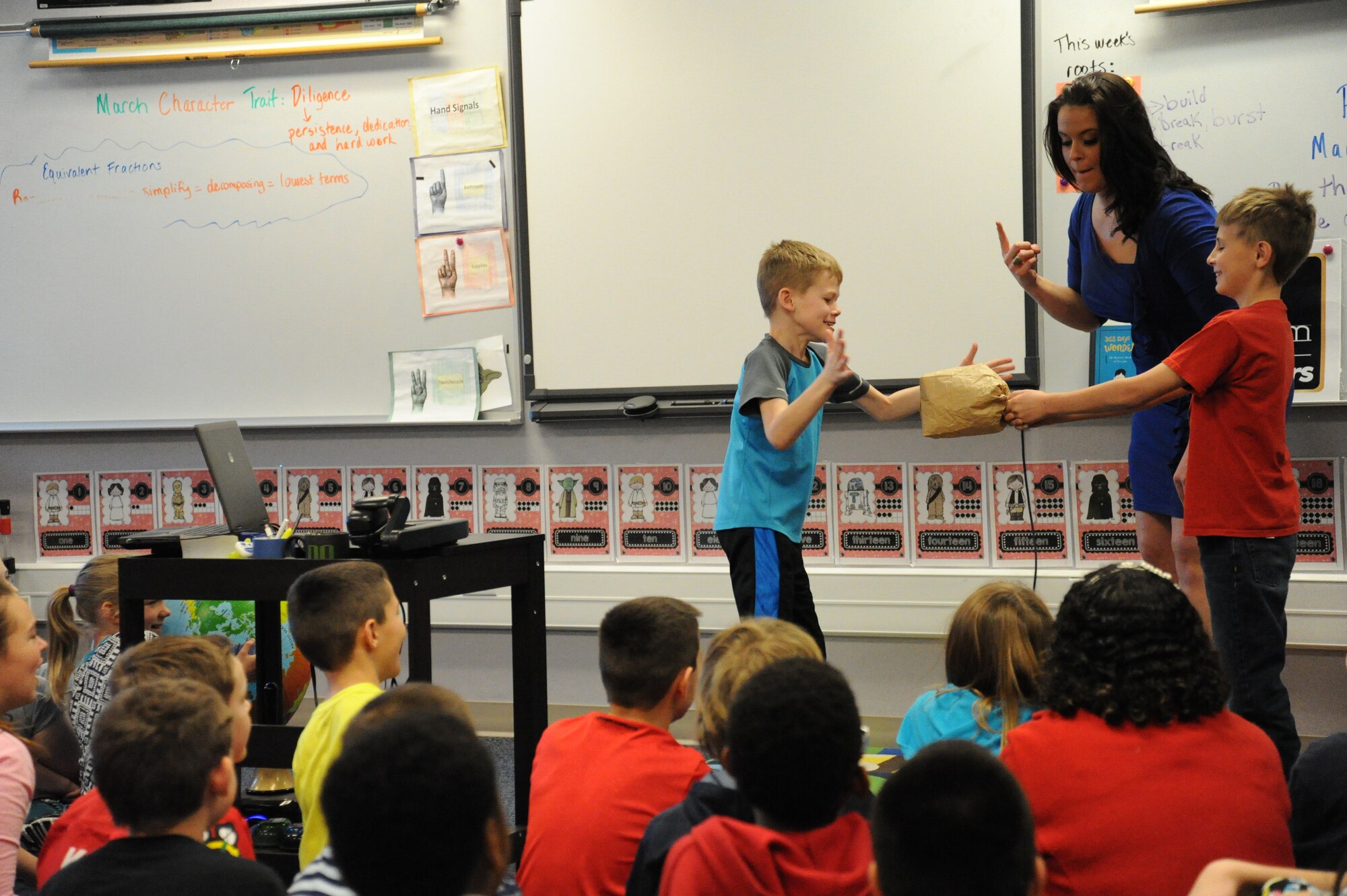 Katie Boer, KREM 2 NEWS weather anchor, has two children demonstrate the sound of thunder by popping a paper bag March 18, 2015, at Fairchild Air Force Base, Wash. Boer taught the students lightning travels faster than sound and is why thunder is heard after lightning is seen. (U.S. Air Force photo/Airman 1st Class Nicolo J. Daniello)