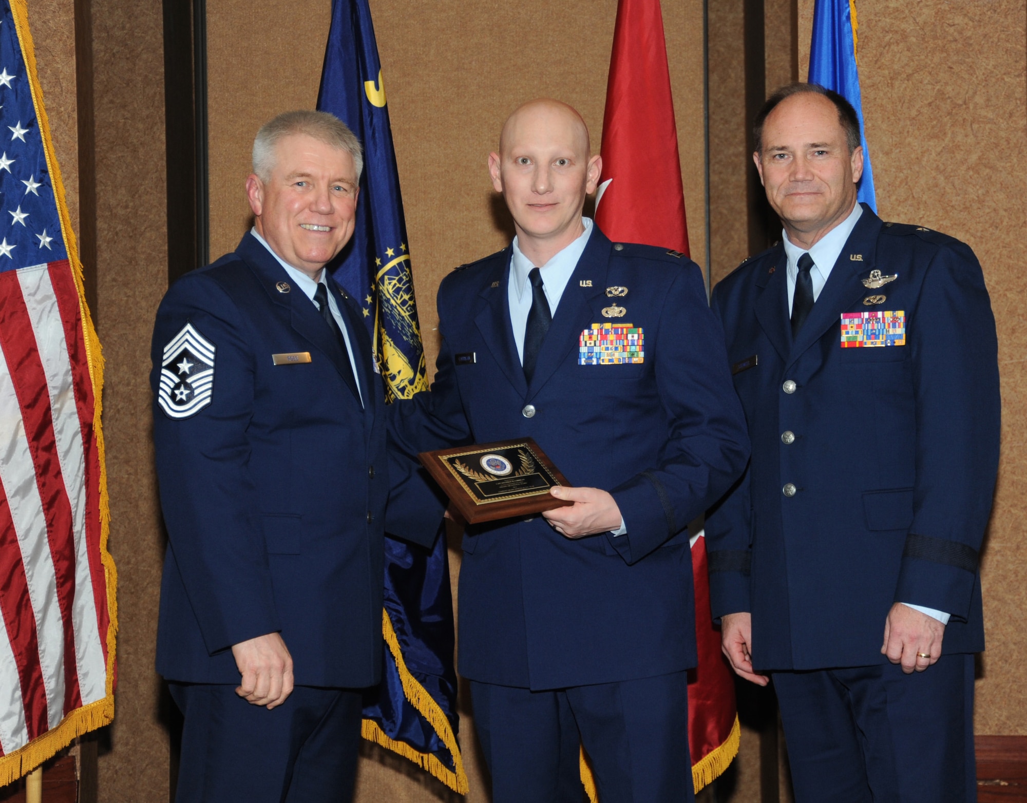 Oregon Air National Guard Capt. Jonathan Corrigan, assigned to the 142nd Civil Engineer Squadron, center, is presented with the overall Oregon Air National Guard Outstanding Company Grade Officer of the Year Award, from 173rd Fighter Wing Command Chief Master Sgt. Danny Ross, left, and Air Component Commander Brig. Gen. Michael Stencel, right, during the 21st Annual Oregon Air National Guard Awards Banquet, March 14, 2015, Portland, Ore. (U.S. Air National Guard photo by Tech. Sgt. Emily Thompson, 142nd Fighter Wing Public Affairs/Released)