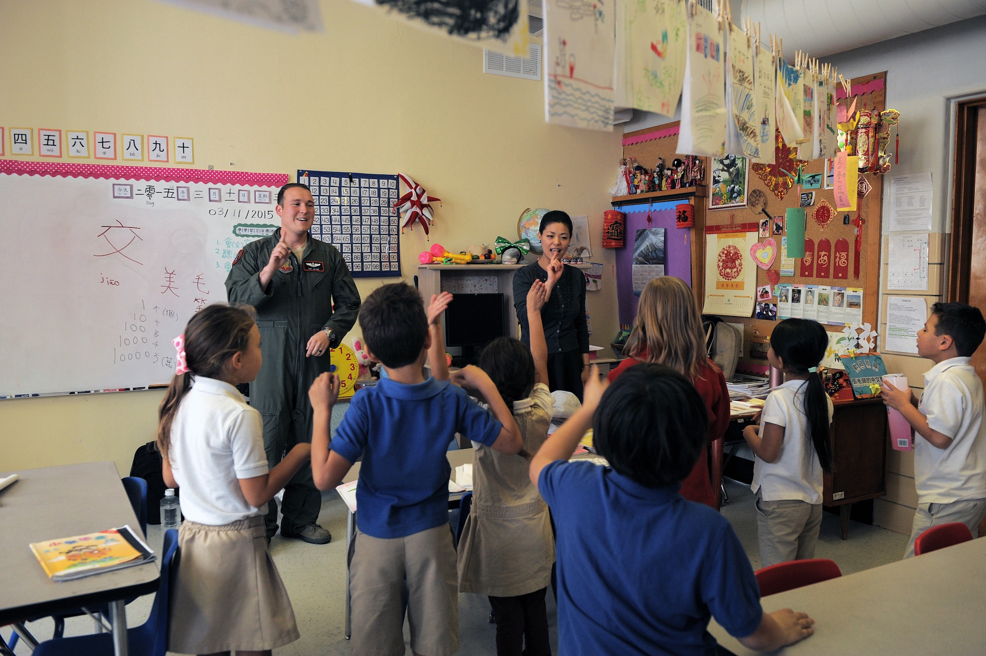 U.S. Air Force Tech. Sgt. Jonathan Roe, 55th Electronic Combat Group Chinese linguist, and Hsin-Fen Chang, International School of Tucson Chinese teacher, recite a Chinese poem with students at the International School of Tucson in Tucson, Ariz., March 11, 2015. Roe has been volunteering to assist the students with the study of the Chinese language since January. (U.S. Air Force photo by Airman 1st Class Chris Drzazgowski/Released) 