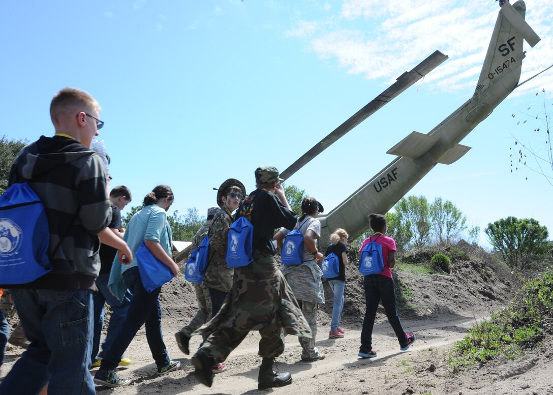 Children exit a replica Afghanistan village as they pass a downed military helicopter during the Jr. Raptor event March 14 at Tyndall. Air Force service members educated children on what goes on during a deployment and what can be expected. (U.S. Air Force photo by Airman 1st Class Ty-Rico Lea/Released)