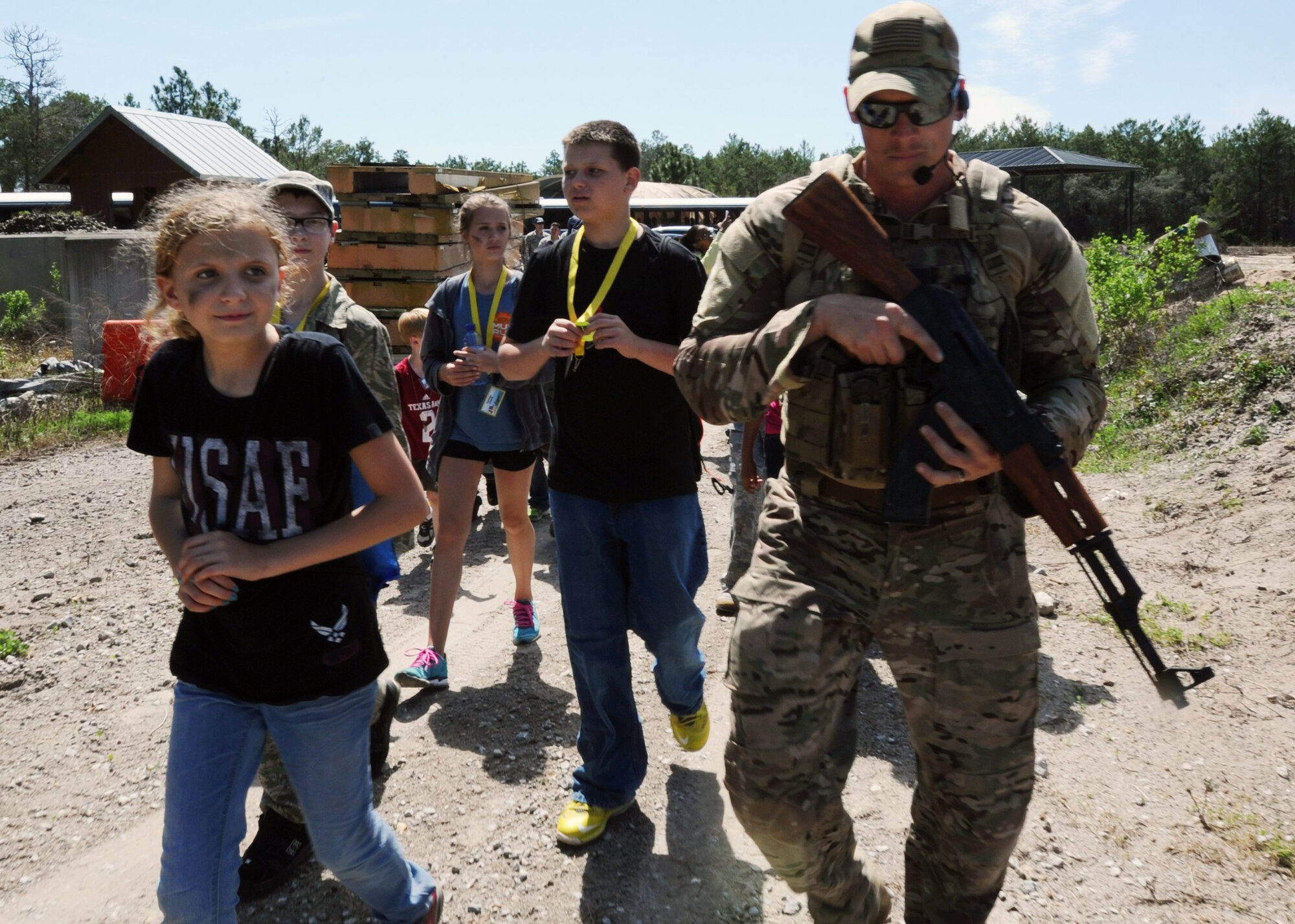 Staff Sgt. Micah Price, 823rd Red Horse Squadron explosive ordnance disposal contingency instructor escorts children through a replica Afghanistan village during the Jr. Raptor event March 14 at Tyndall. The program allowed children of military members to experience a deployment while incorporating different elements such as a commander's brief and physical training. (U.S. Air Force photo by Airman 1st Class Ty-Rico Lea/Released)