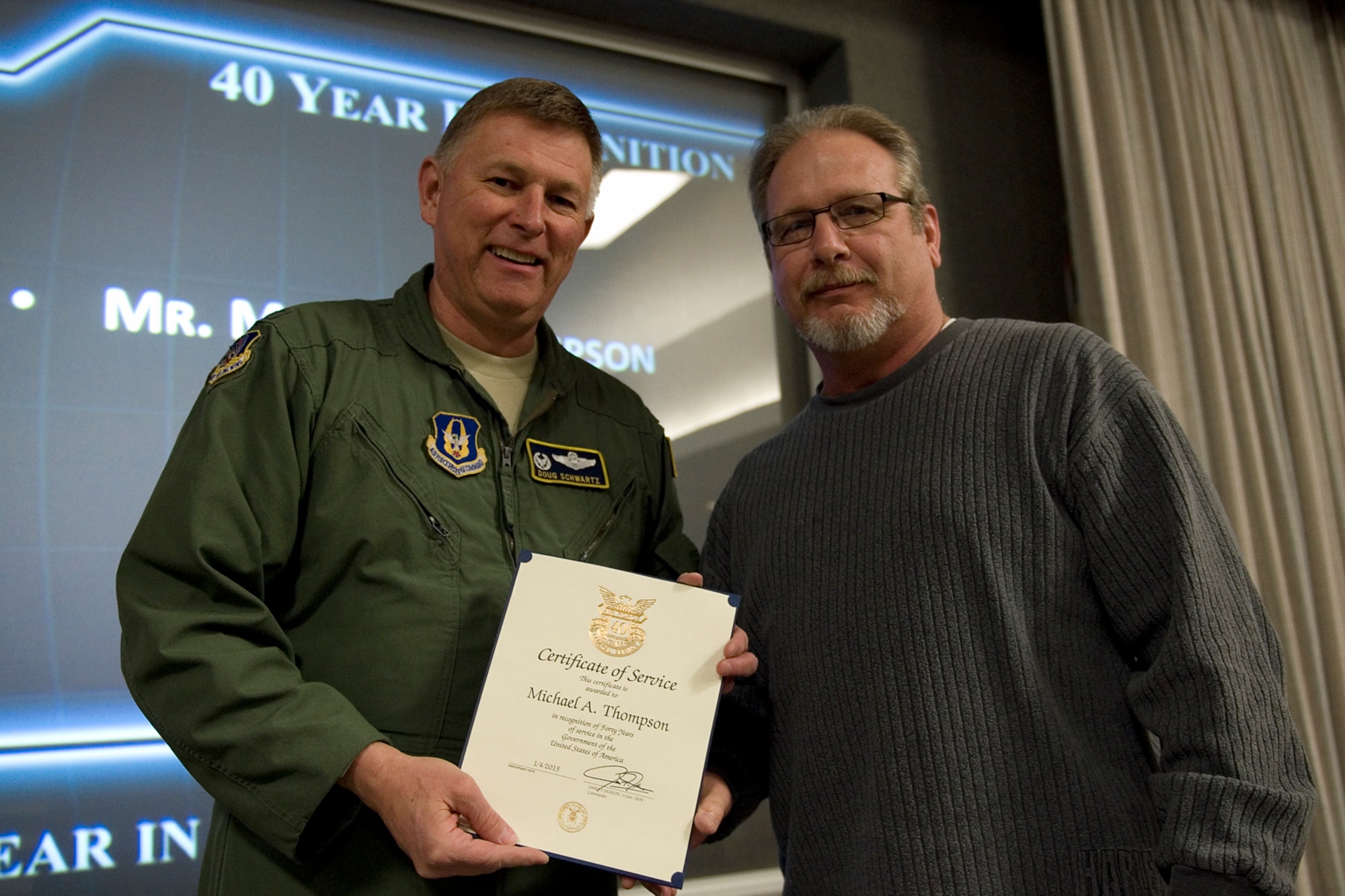 Col. Doug Schwartz, 434th Air Refueling Wing commander, presents Michael Thompson, 434th Operations Support Squadron, with a certificate of service for completing 40 years as a federal employee during a civilian commander's call at Grissom Air Reserve Base, Ind., March. 13, 2015. Civil service employees are an essential part Grissom and serve critical roles in maintaining unit readiness and daily operations. (U.S. Air Force photo/Tech. Sgt. Benjamin Mota)