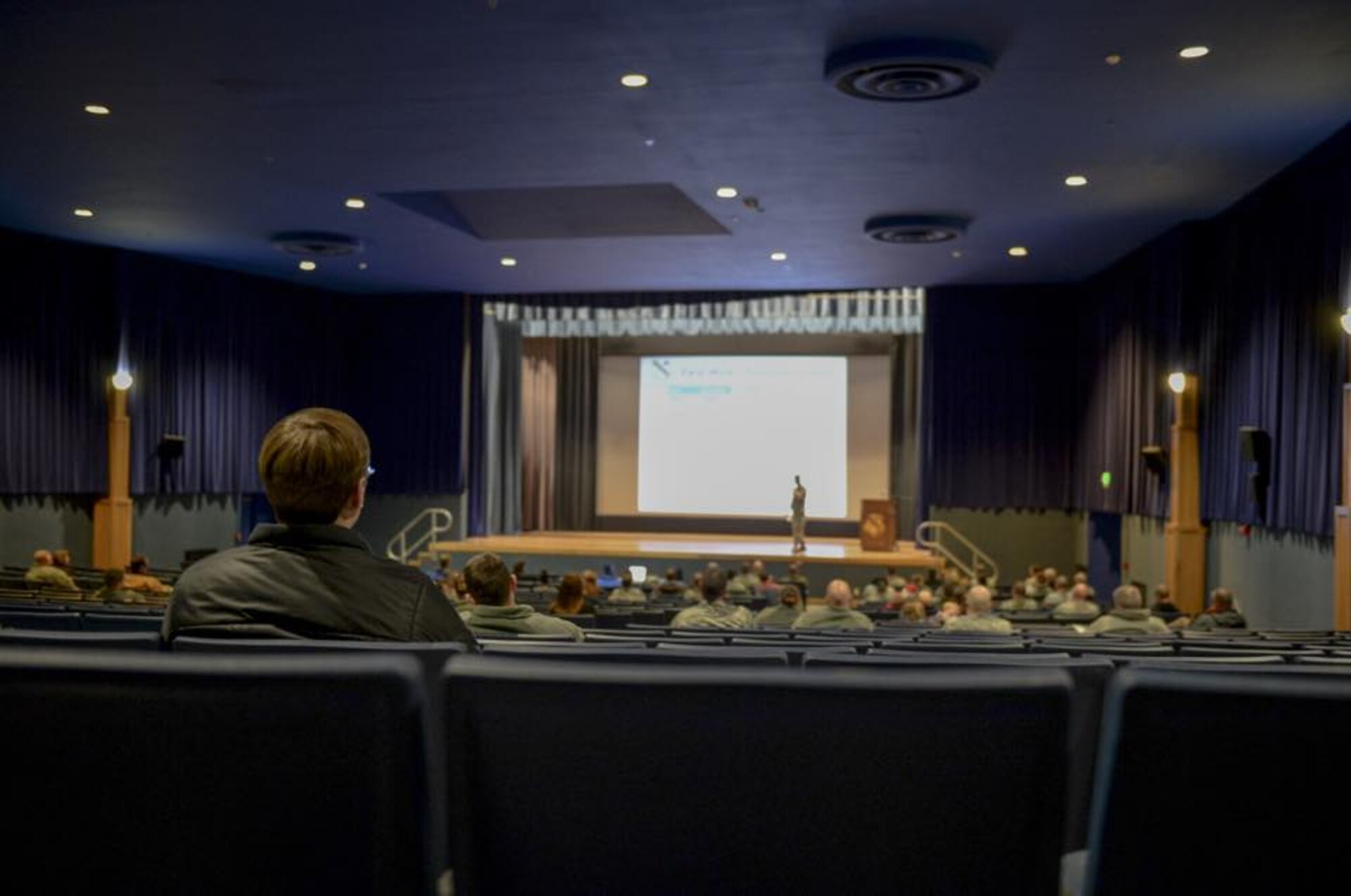 Eielson housing residents listen to leaders address upcoming changes to the French Creek and Moose Lake housing area at the Ernie Walker Theater, Eielson Air Force Base, Alaska, March 12, 2015. Base leaders held a town hall meeting to inform residents of ongoing construction projects to help bring reliable heat to older infrastructure. (U.S. Air Force photo by 1st Lt. Elias Zani/Released)