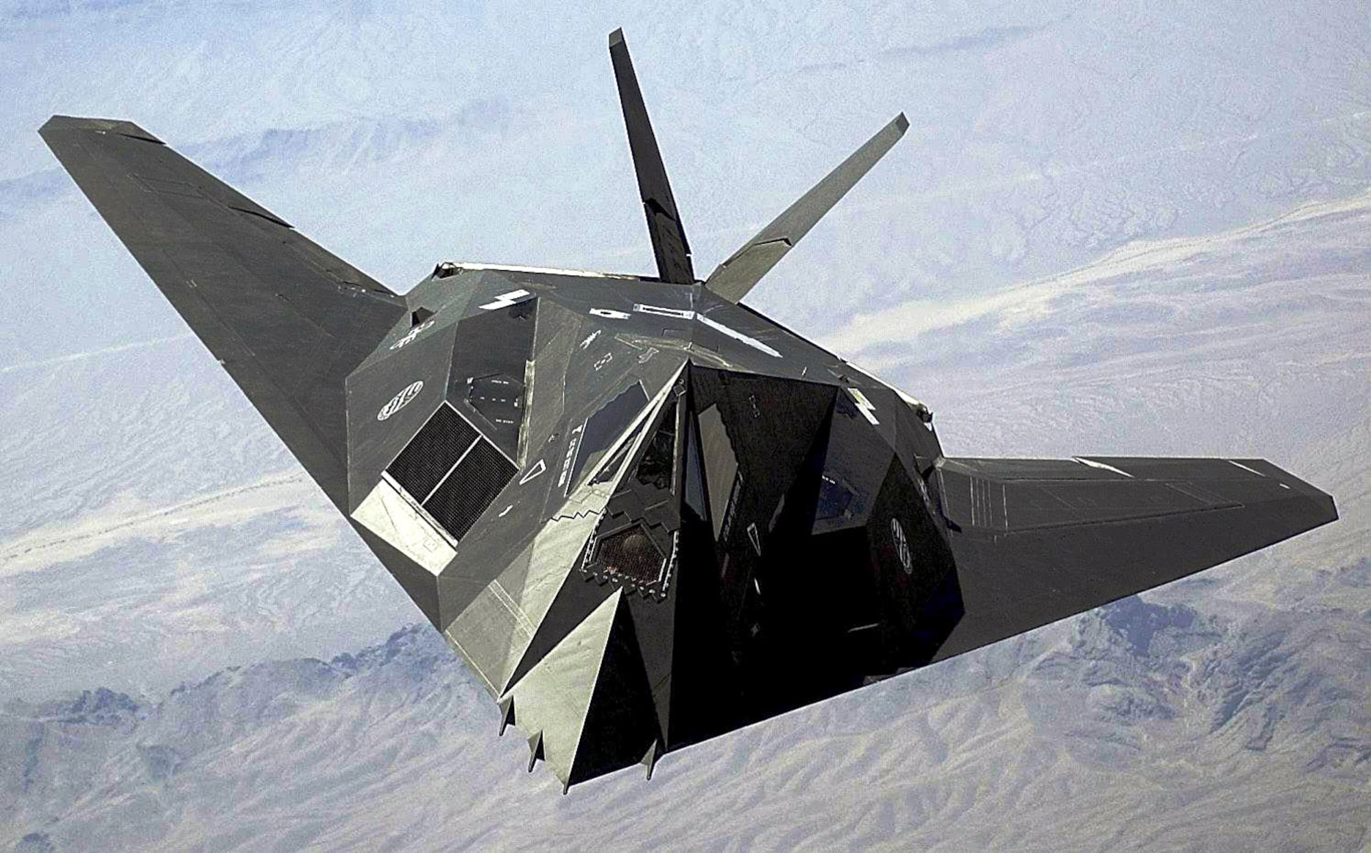 An F-117 Nighthawk flies over the Nevada desert. The unique design of the single-seat F-117 provides exceptional combat capabilities. The fighter can employ a variety of weapons and is equipped with sophisticated navigation and attack systems integrated into a digital avionics suite that increases mission effectiveness and reduces pilot workload. (U.S. Air Force photo/Staff Sgt. Aaron D. Allmon II)