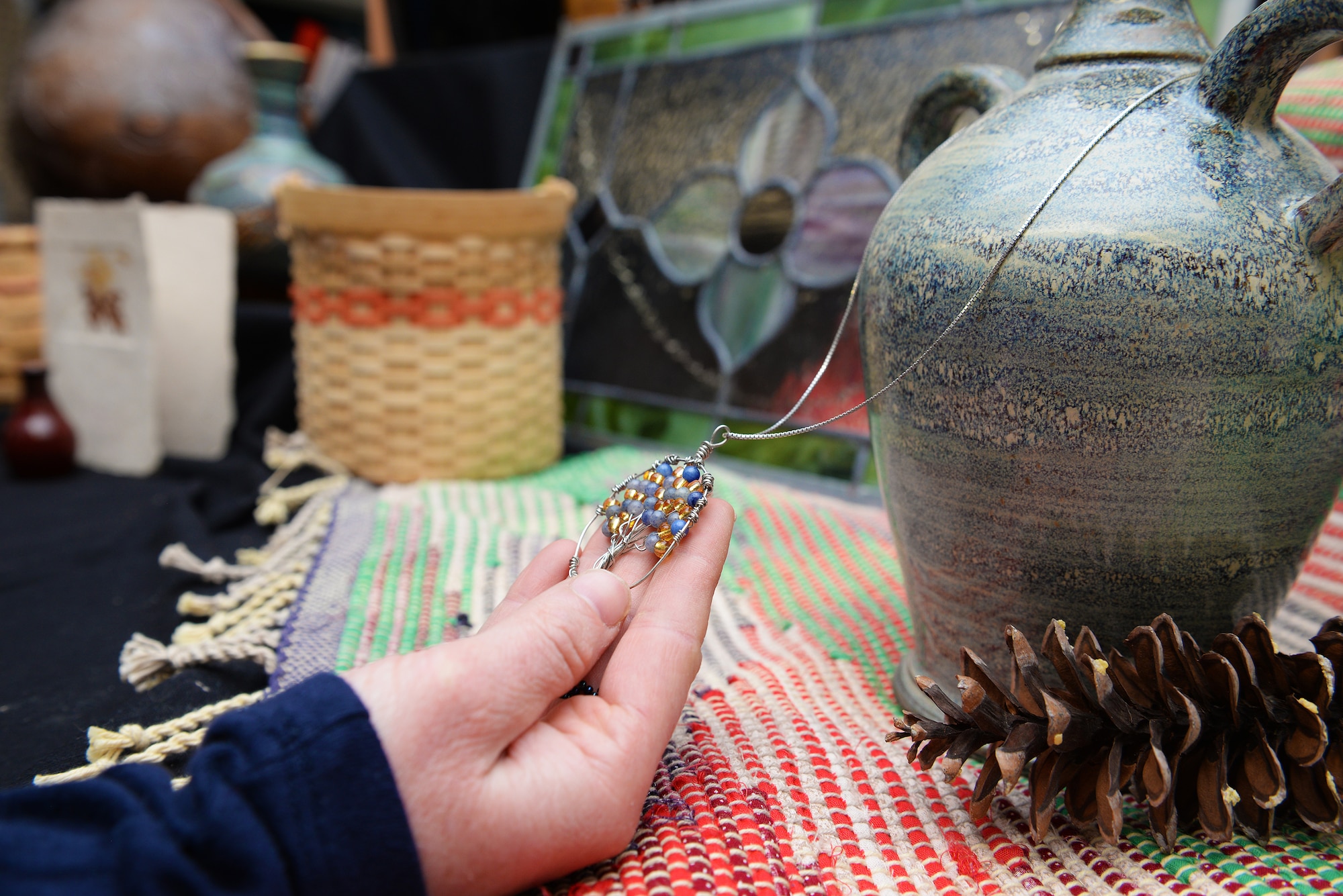 Becky McDaniel, Jewelry Demonstrator at the upcoming Arts and Crafts Center Open House, places one of her finished wire wrap necklaces on an art display, Scott Air Force Base, Illinois, March 13, 2015. The open house is March 21, 2015 from 9 to 4, and will feature 23 artisans showcasing different crafts and hobbies. (U.S. Air Force photo by Airman 1st Class Erica Crossen)